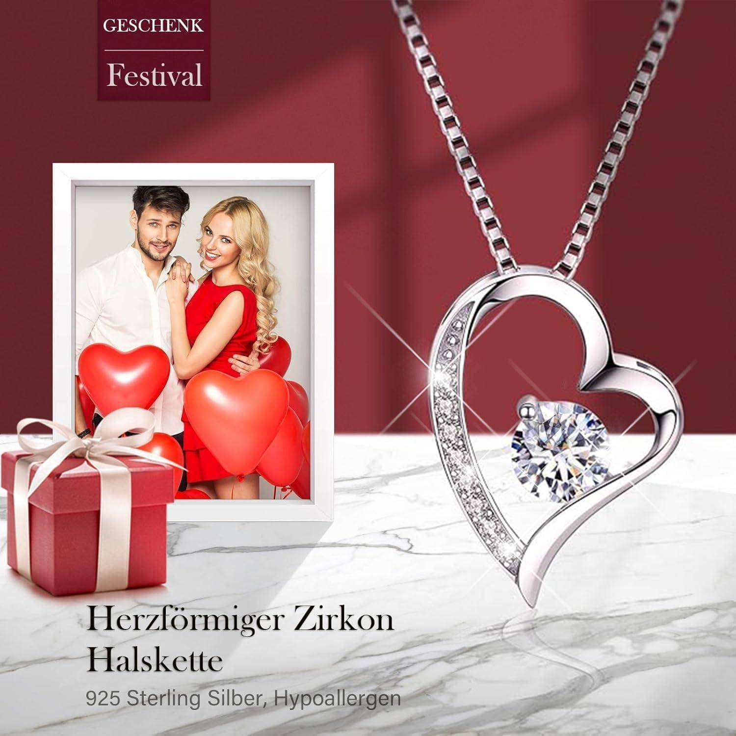 Eine silberne, herzförmige Zirkon-Halskette wird neben einem gerahmten Paarfoto und einer roten Geschenkbox präsentiert. Der deutsche Text bezieht sich auf ein Geschenkfestival.