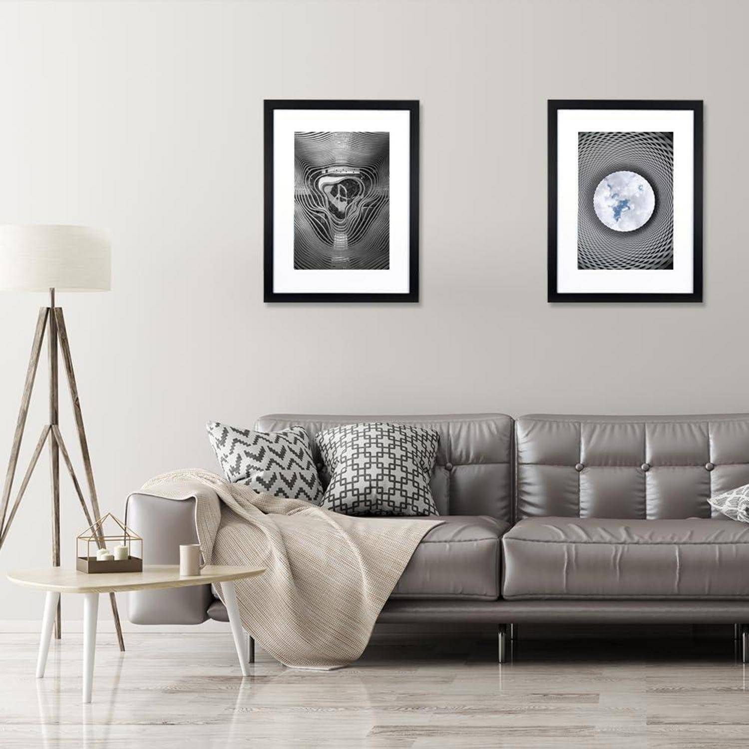 Ein modernes Wohnzimmer mit einem grauen Sofa, einem hellfarbenen Teppich, einer Stehlampe und zwei abstrakten schwarz-weißen gerahmten Kunstwerken an der Wand.