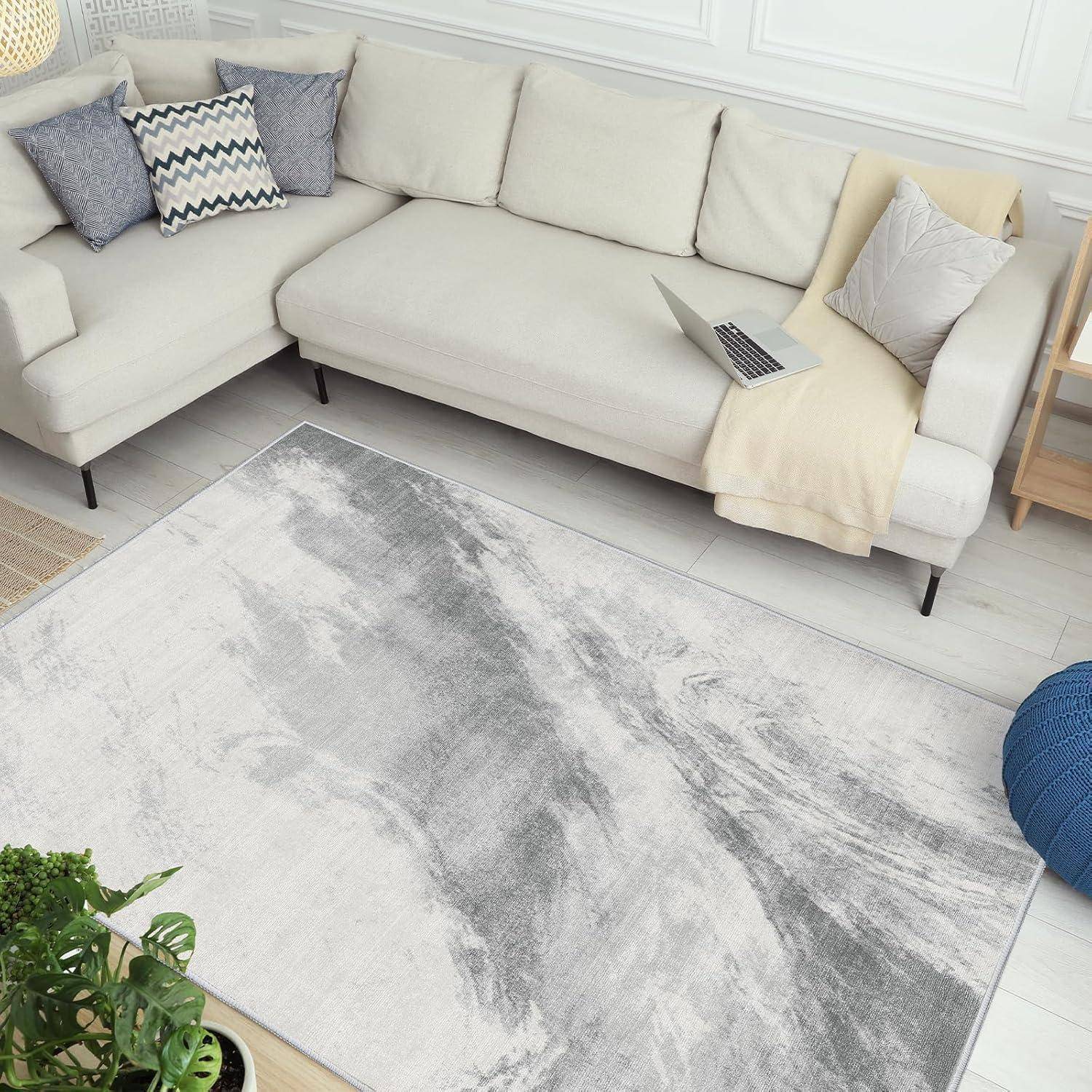 Ein gemütliches Wohnzimmer mit einem weißen Ecksofa, geschmückt mit Kissen in Beige- und Blautönen, einem grauen marmorierten Teppich und einem Laptop auf dem Sofa.