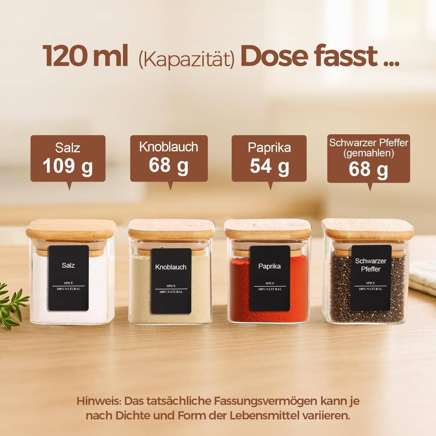 Vier rechteckige Gläser mit den Aufschriften „Salz 109 g", „Knoblauch 68 g"", „Paprika 54 g"", „Schwarzer Pfeffer 68 g"" stehen auf einer Holzoberfläche.