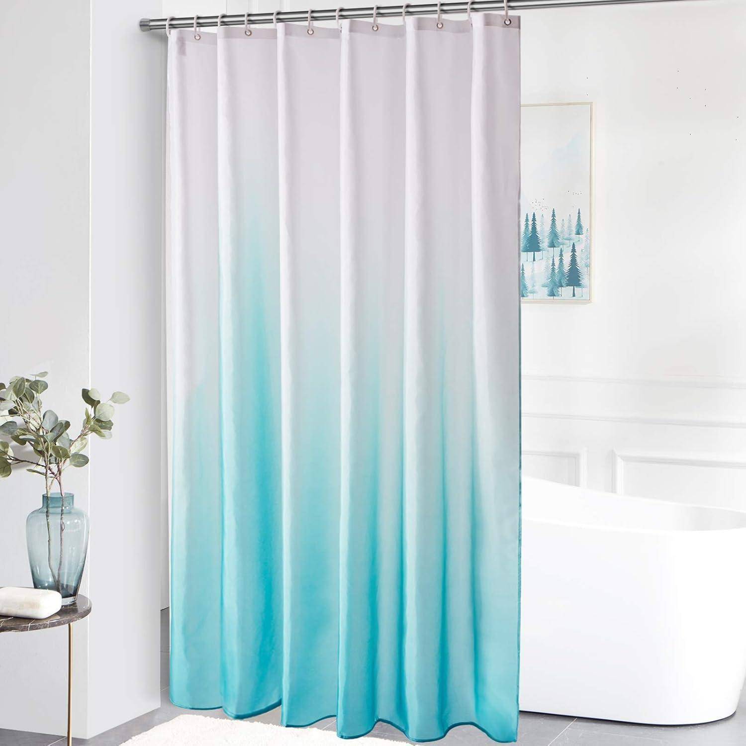 Duschvorhang mit einem blauen Ombré-Design, der in einem modernen Badezimmer mit weißen Wänden und einem gerahmten Bild einer Winterlandschaft hängt.