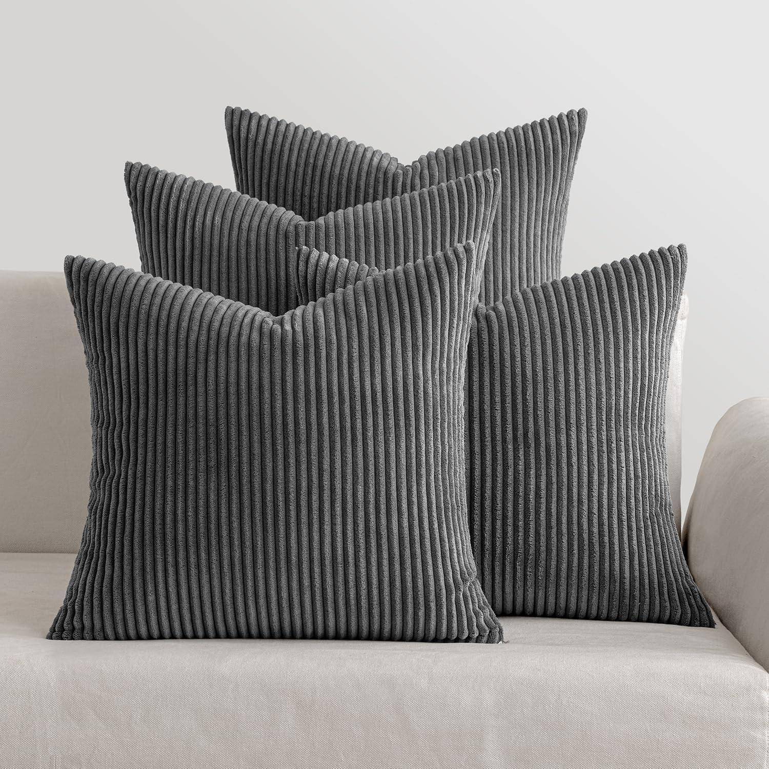 Vier graue, vertikal gestreifte Kissen, die auf einem beigen Sofa in einer Wohnzimmereinrichtung angeordnet sind.