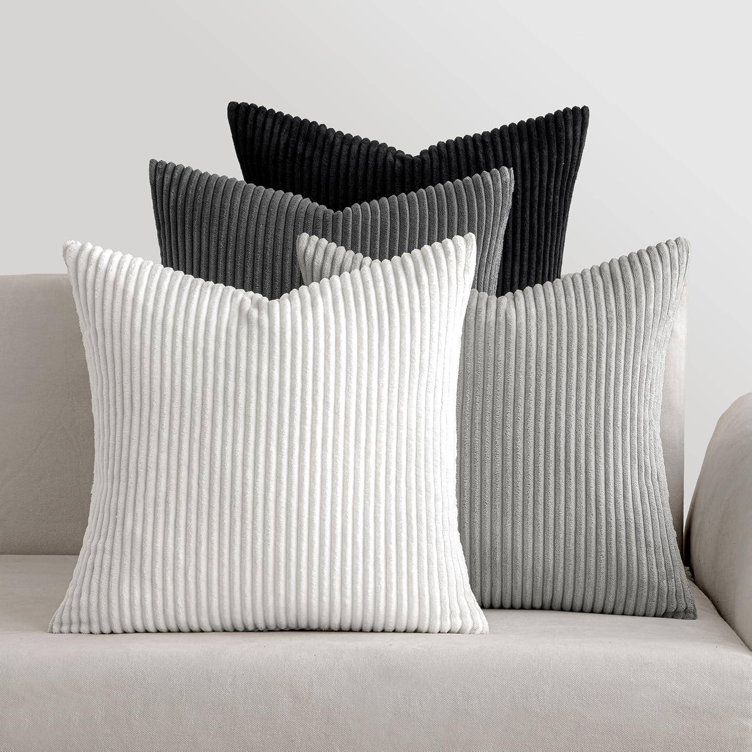 Drei gerippte Kissen auf einem hellgefärbten Sofa: zwei weiße und ein dunkelgraues, die Textur und kontrastierende Töne in die minimalistische Umgebung bringen.