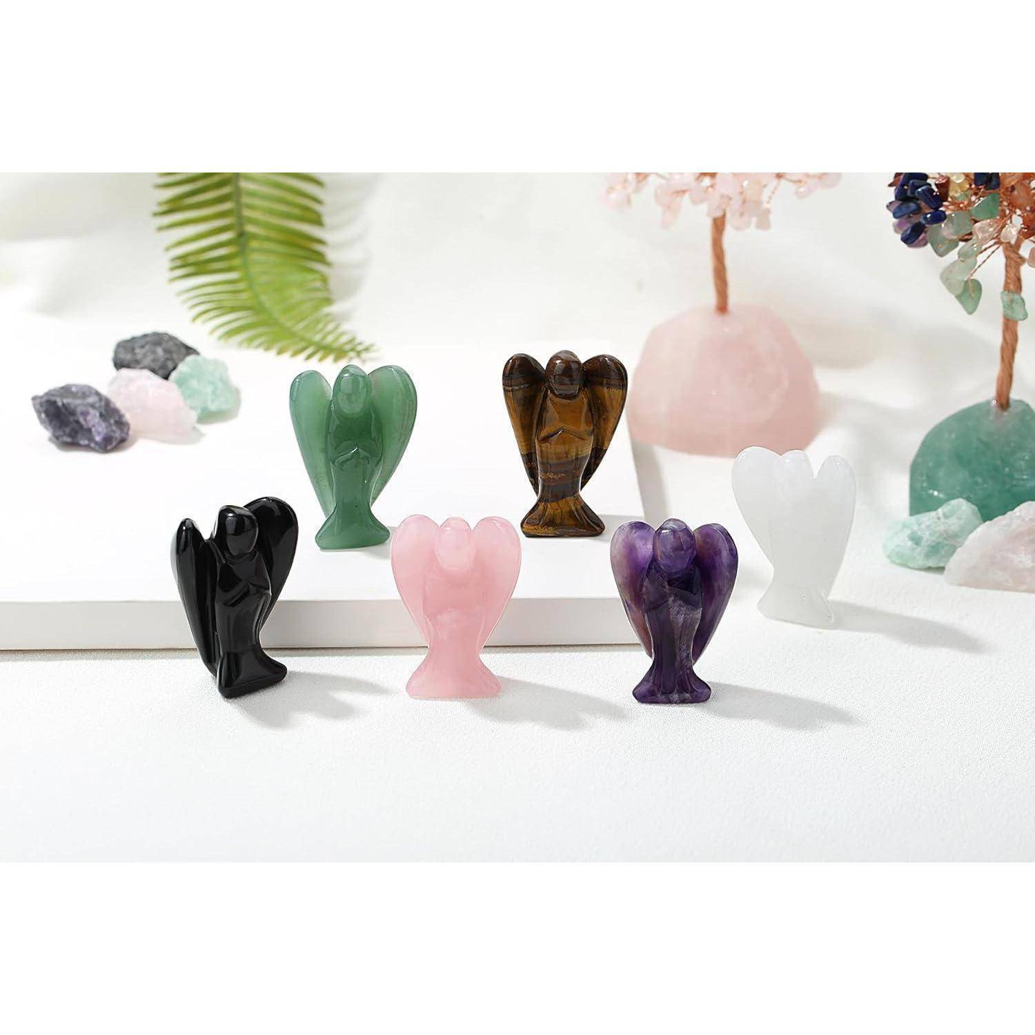 Kleine geschnitzte Steingel-Figuren in verschiedenen Farben, darunter Schwarz, Rosa, Grün und Lila, auf einer weißen Oberfläche ausgestellt.