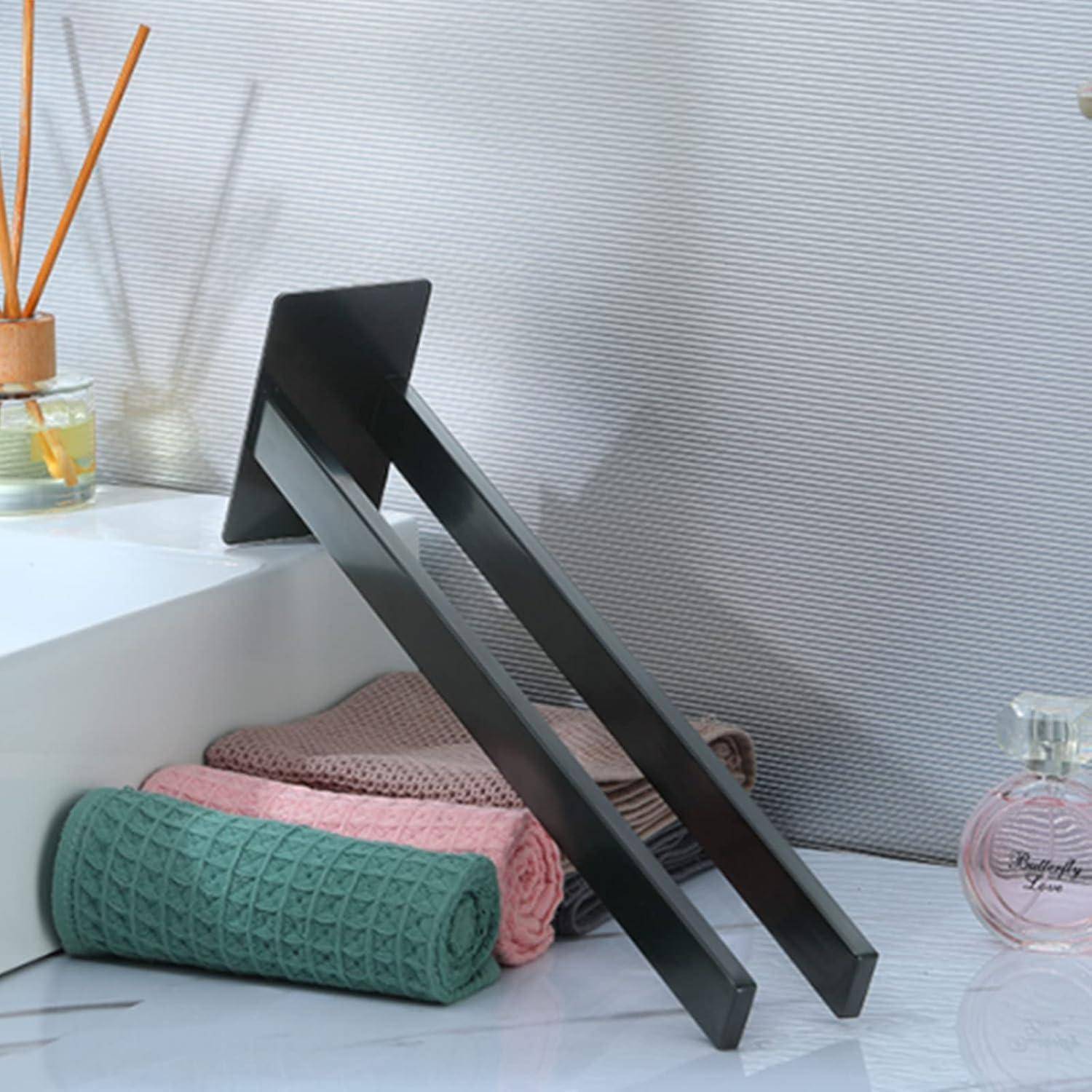 Ein moderner schwarzer Buchständer hält ein Tablet, das auf einem weißen Schreibtisch neben zusammengelegten Handtüchern, einem Duftdiffuser und einer kleinen Parfümflasche steht.