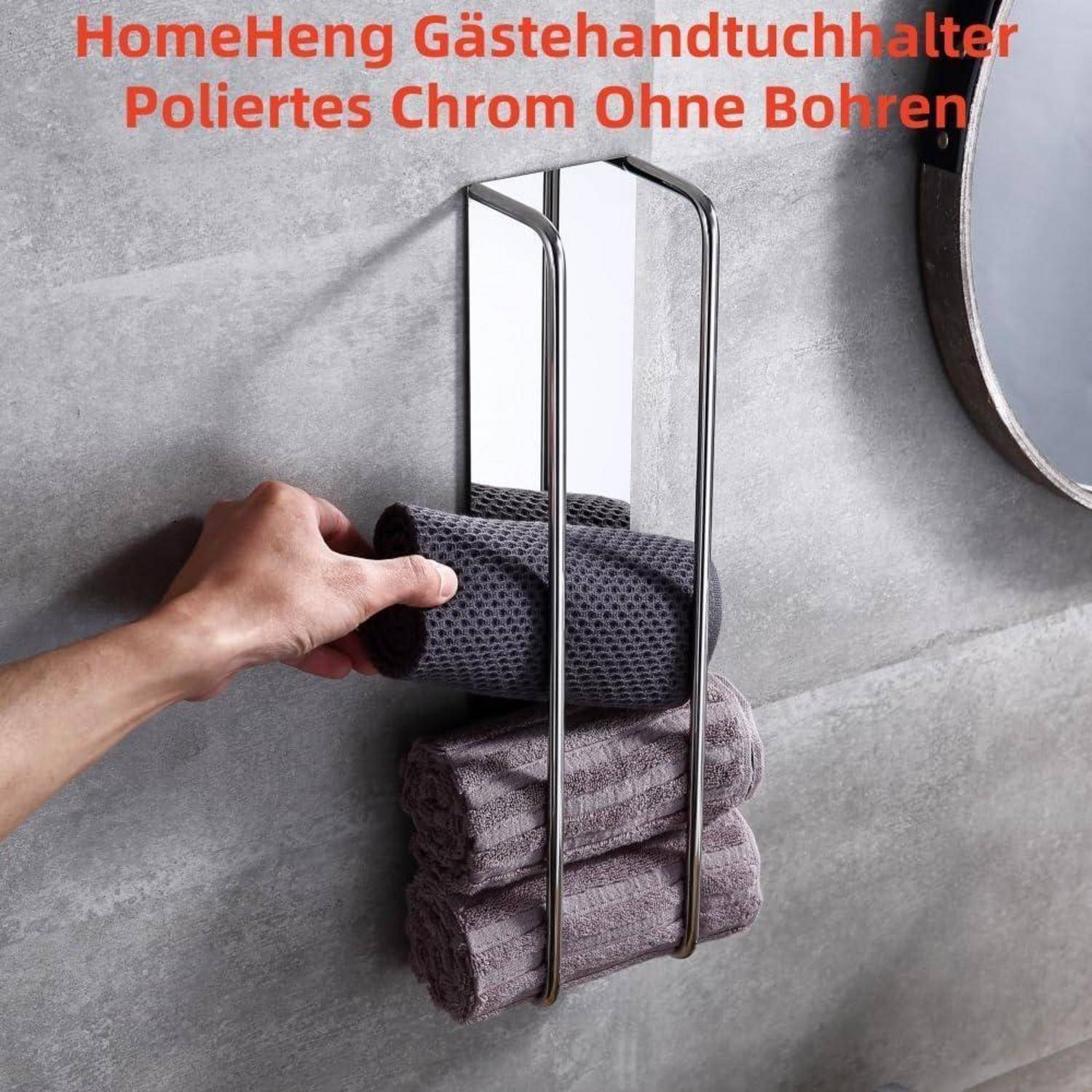 Eine Hand legt ein graues Handtuch auf einen an der Wand montierten verchromten Handtuchhalter. Drei Handtücher sind darunter ordentlich gestapelt.