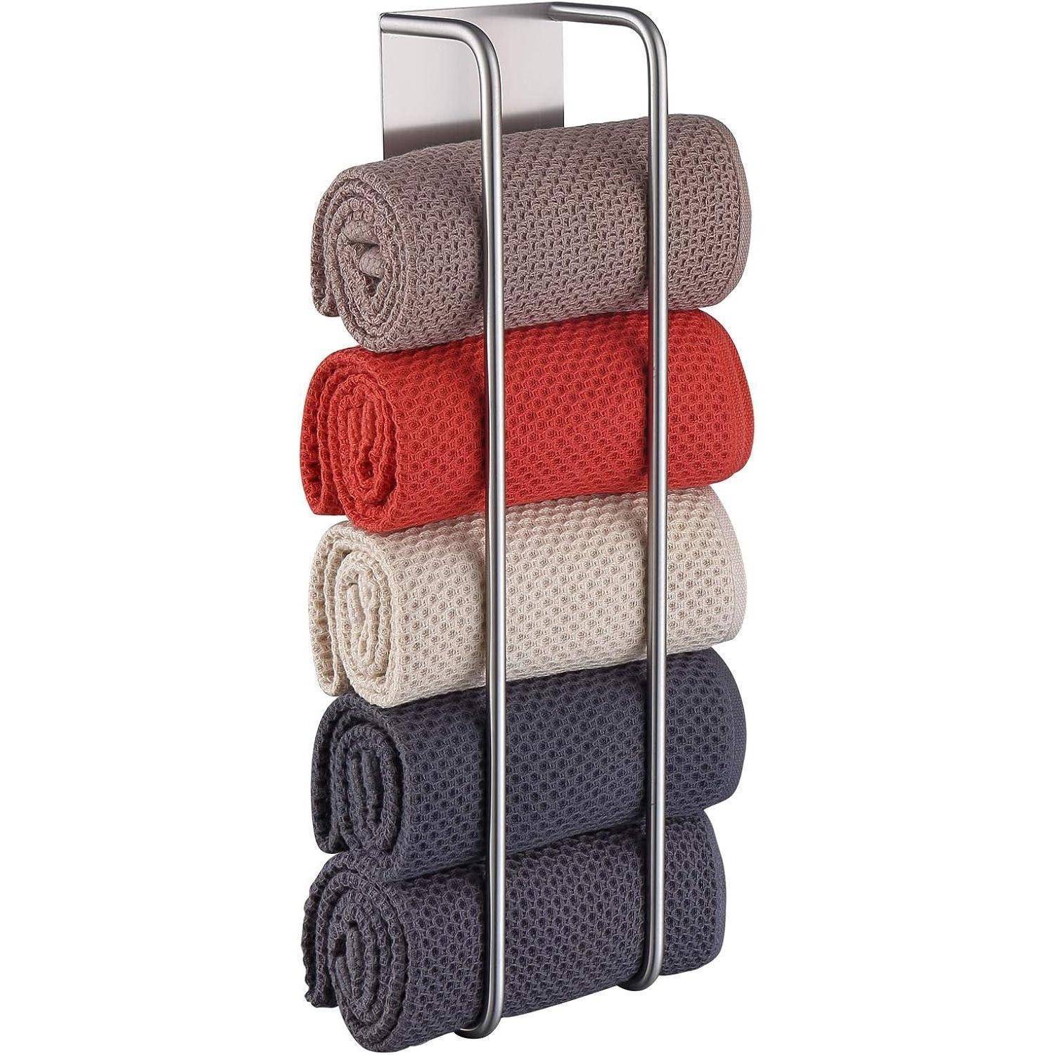 Fünf aufgerollte Handtücher in Rot, Beige und Dunkelgrau auf einem Handtuchhalter aus Metall.