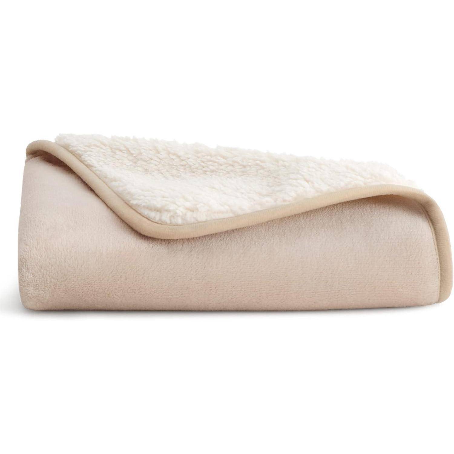 Eine gefaltete hellbeige Fleecedecke mit einer weichen, flauschigen Textur auf einer Seite, die ihr warmes und gemütliches Aussehen zur Geltung bringt.