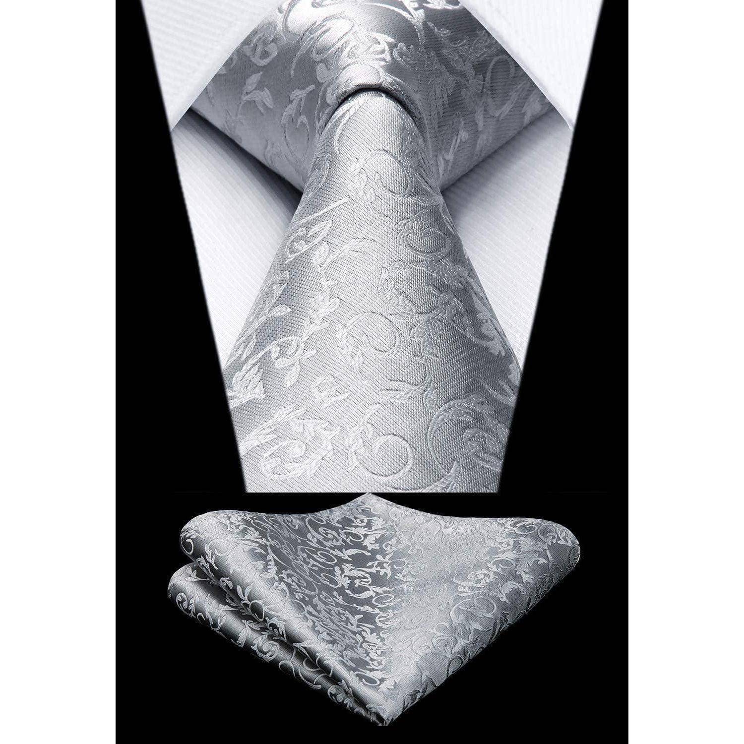 Eine silberne Paisley-gemusterte Krawatte und das passende Einstecktuch vor schwarzem Hintergrund, die das elegante Design und die Textur betonen.
