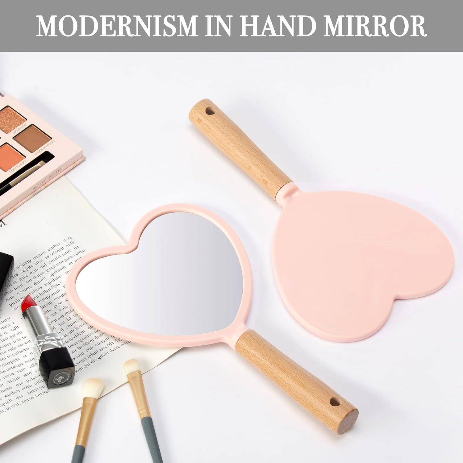 Ein herzförmiger Handspiegel mit einem Holzgriff ist von Make-up-Produkten umgeben, unter einer Überschrift, die 