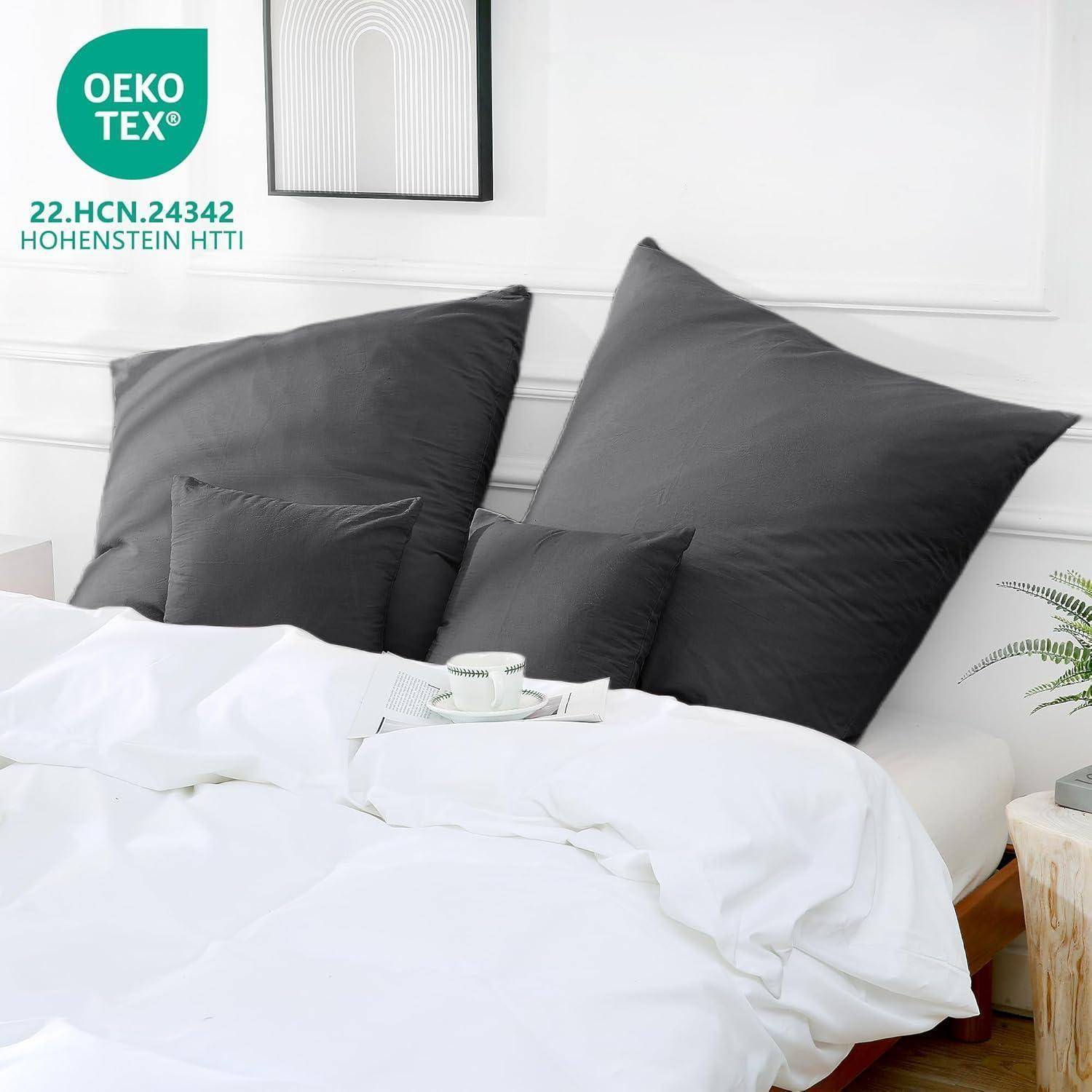 Ein ordentlich gemachtes Bett mit dunkelgrauen Akzentkissen, gerahmter Kunst an der Wand und einem OEKO-TEX-Zertifizierungsetikett in der Ecke.