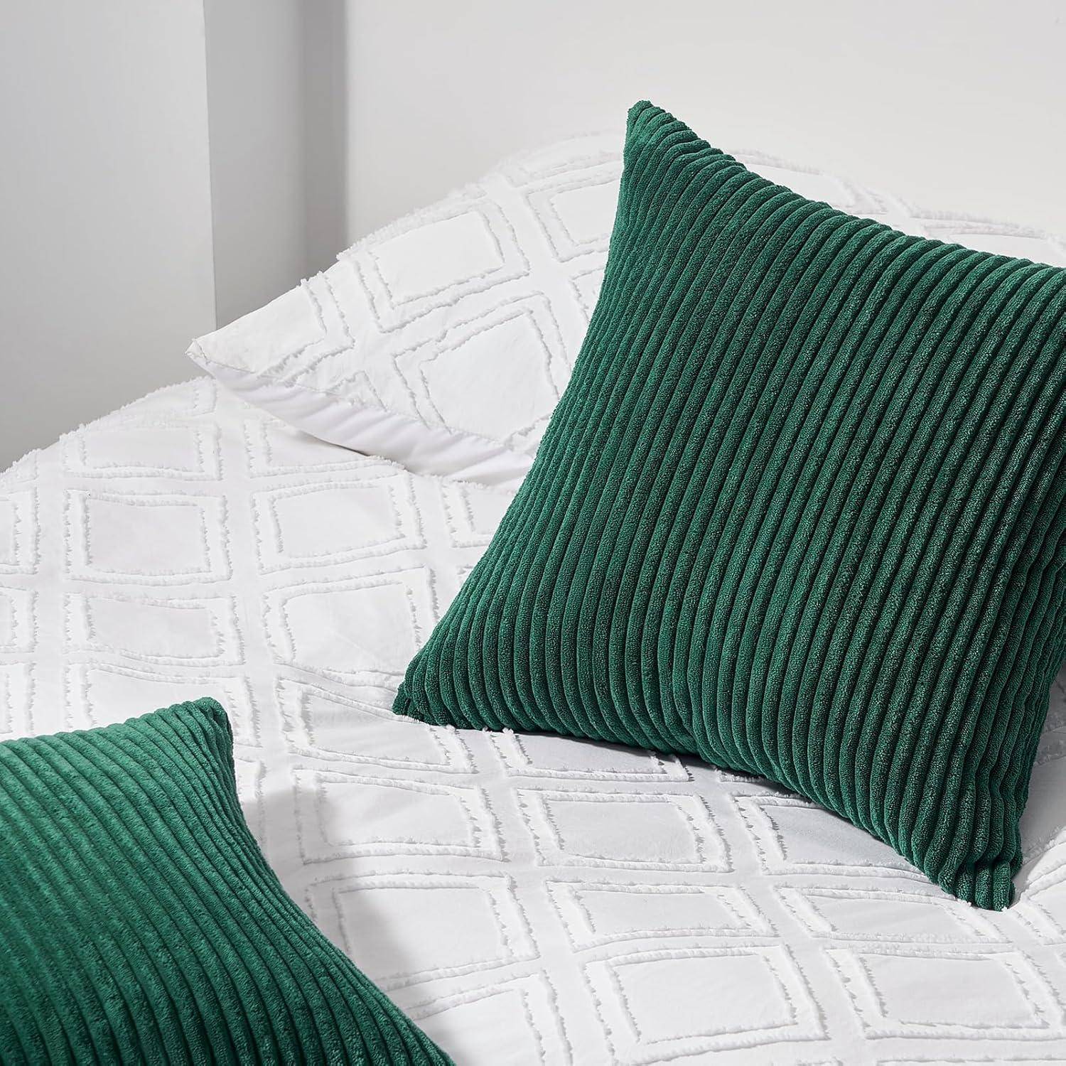 Ein Bett mit einer weißen gesteppten Decke und zwei grünen strukturierten Kissen darauf, was den Eindruck einer gemütlichen und einladenden Umgebung vermittelt.