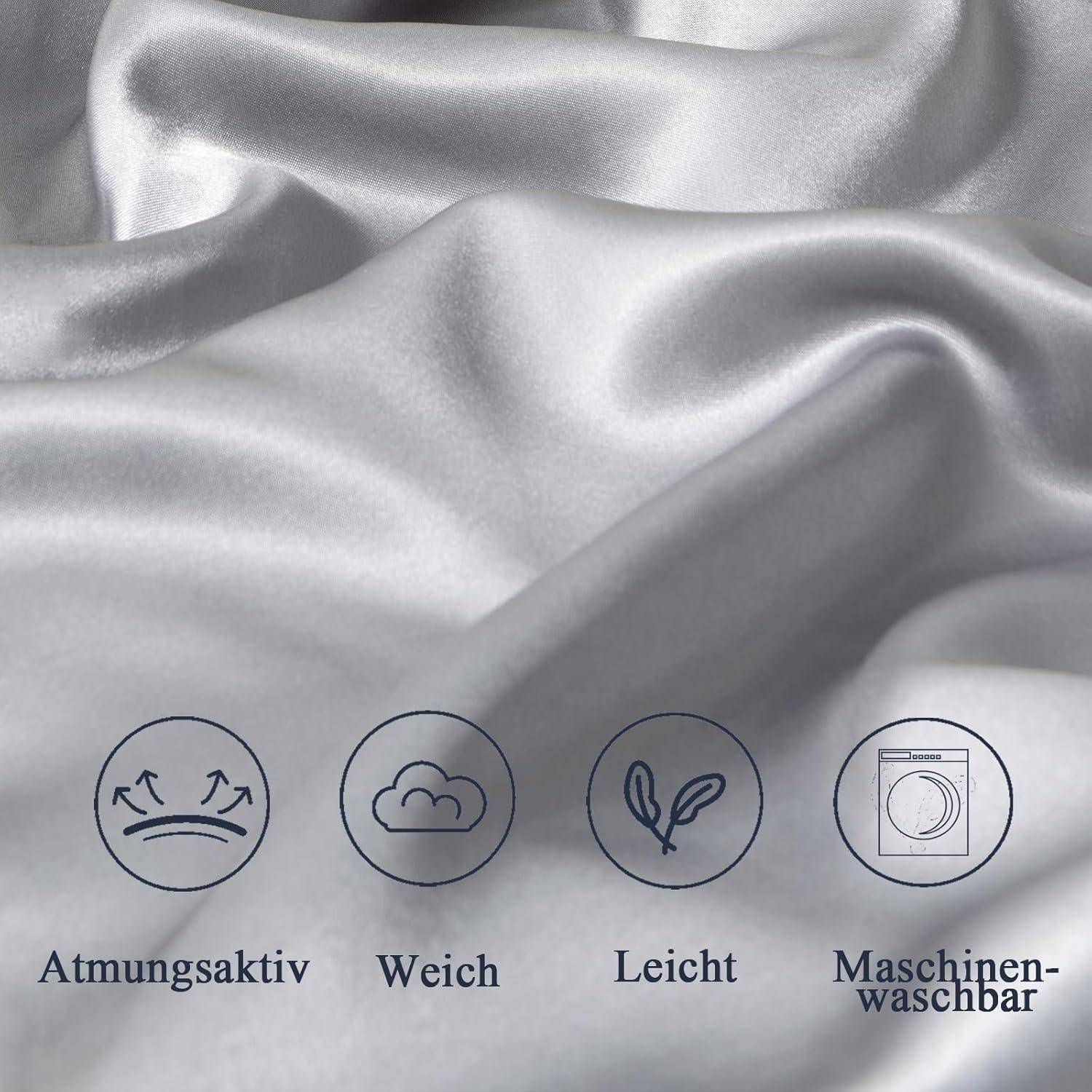 Glatter silberner Stoff mit einem sanften Schimmer, mit Icons und Text darunter: 'Atmungsaktiv', 'Weich', 'Leicht', 'Maschinenwaschbar'.