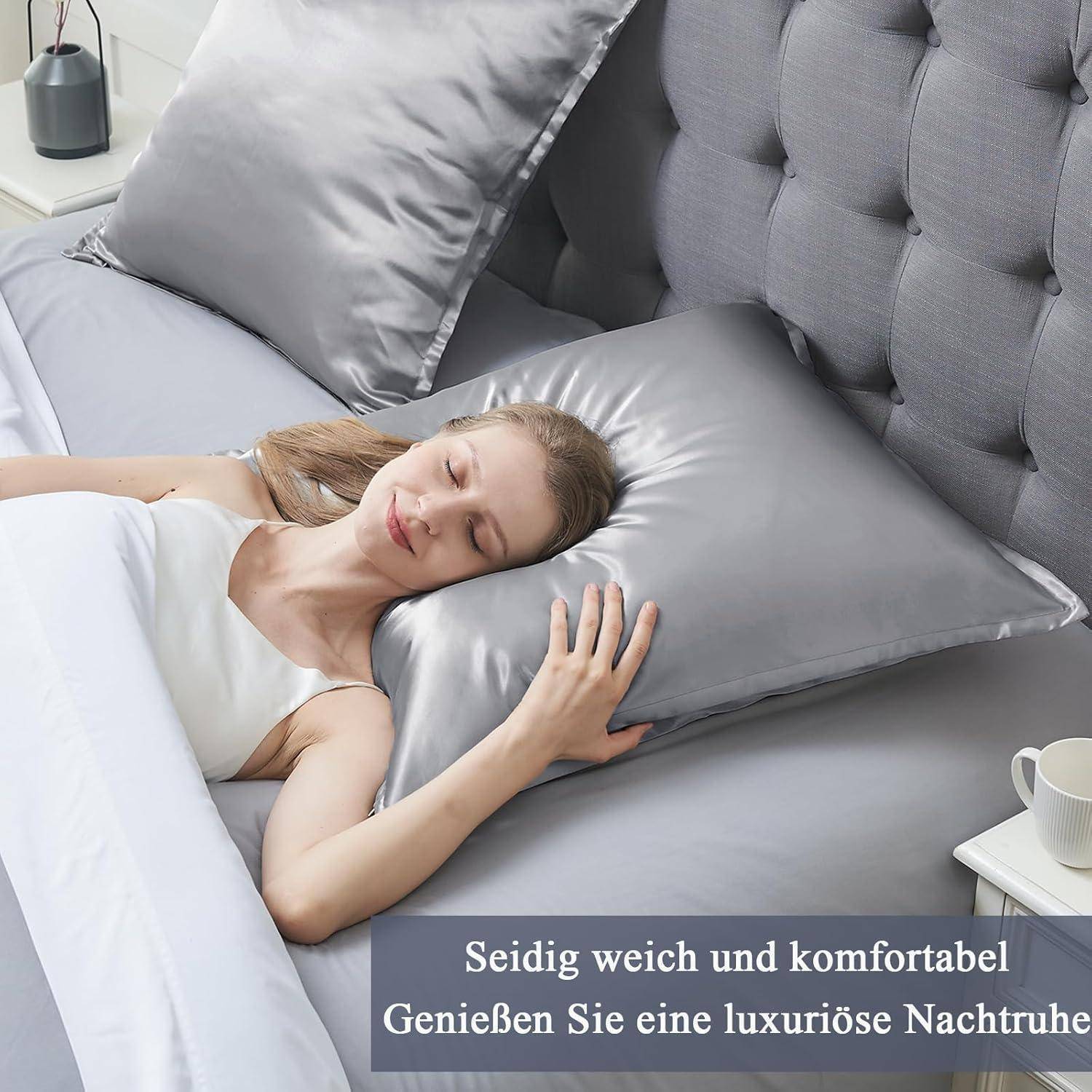 Eine Frau schläft friedlich auf einem Bett mit grauen Satin-Kissenbezügen und Bettwäsche, was Komfort und Luxus vermittelt.