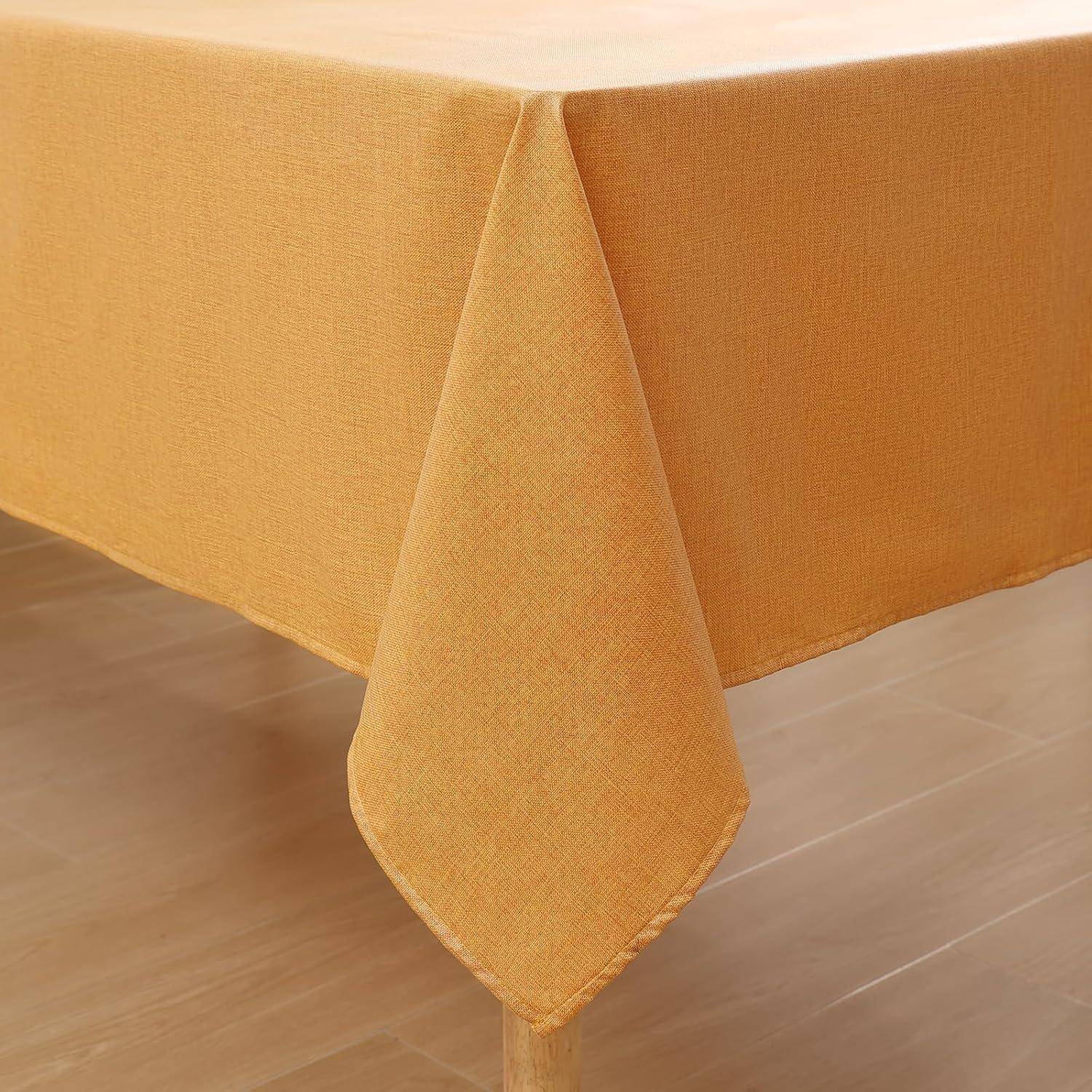Eine orangefarbene Tischdecke auf einem rechteckigen Tisch, die sich gleichmäßig über die Kanten erstreckt, in einem hell erleuchteten Raum mit Holzboden.