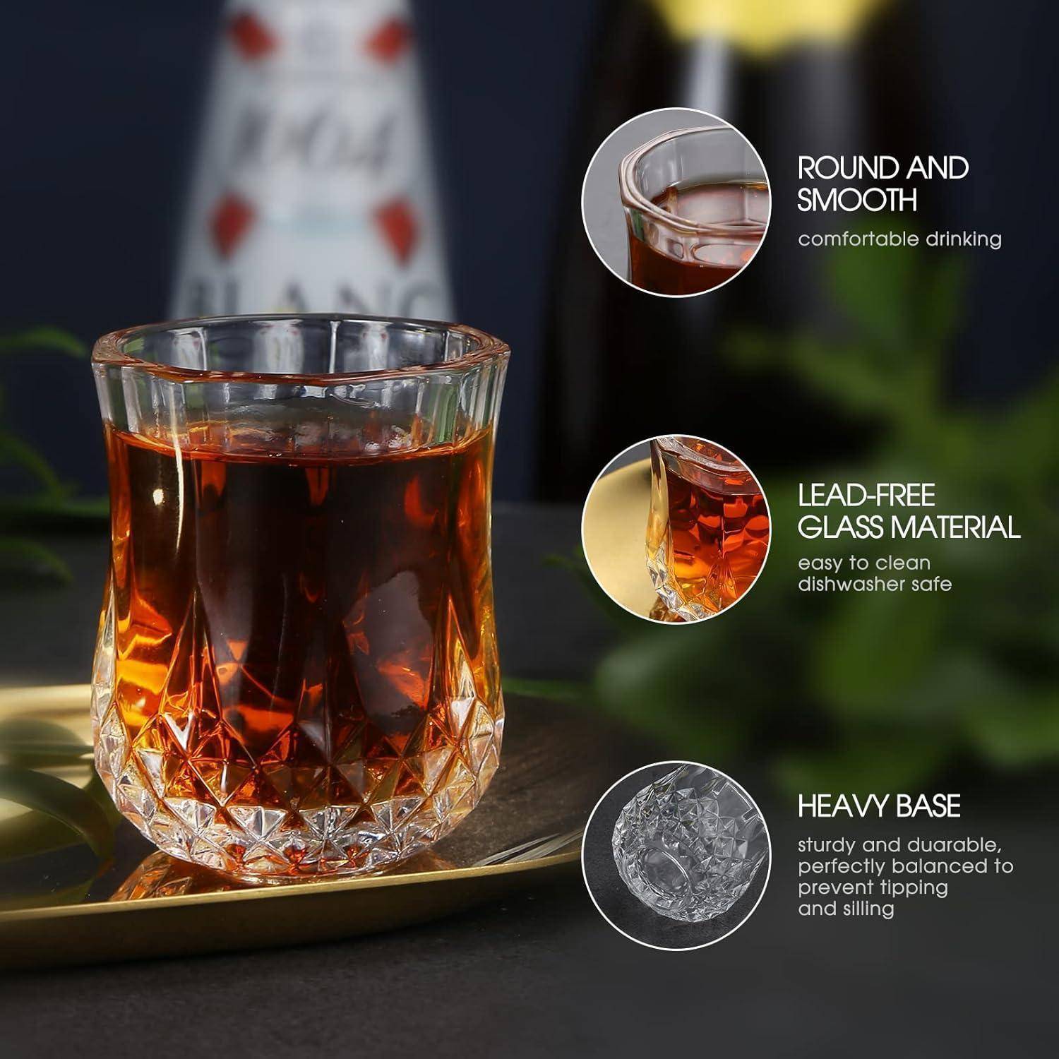 Ein klares Glas, gefüllt mit dunkler Flüssigkeit auf einem Tablett. Der Text hebt seine runde, glatte Form, das bleifreie Material und die schwere Basis für Stabilität hervor.