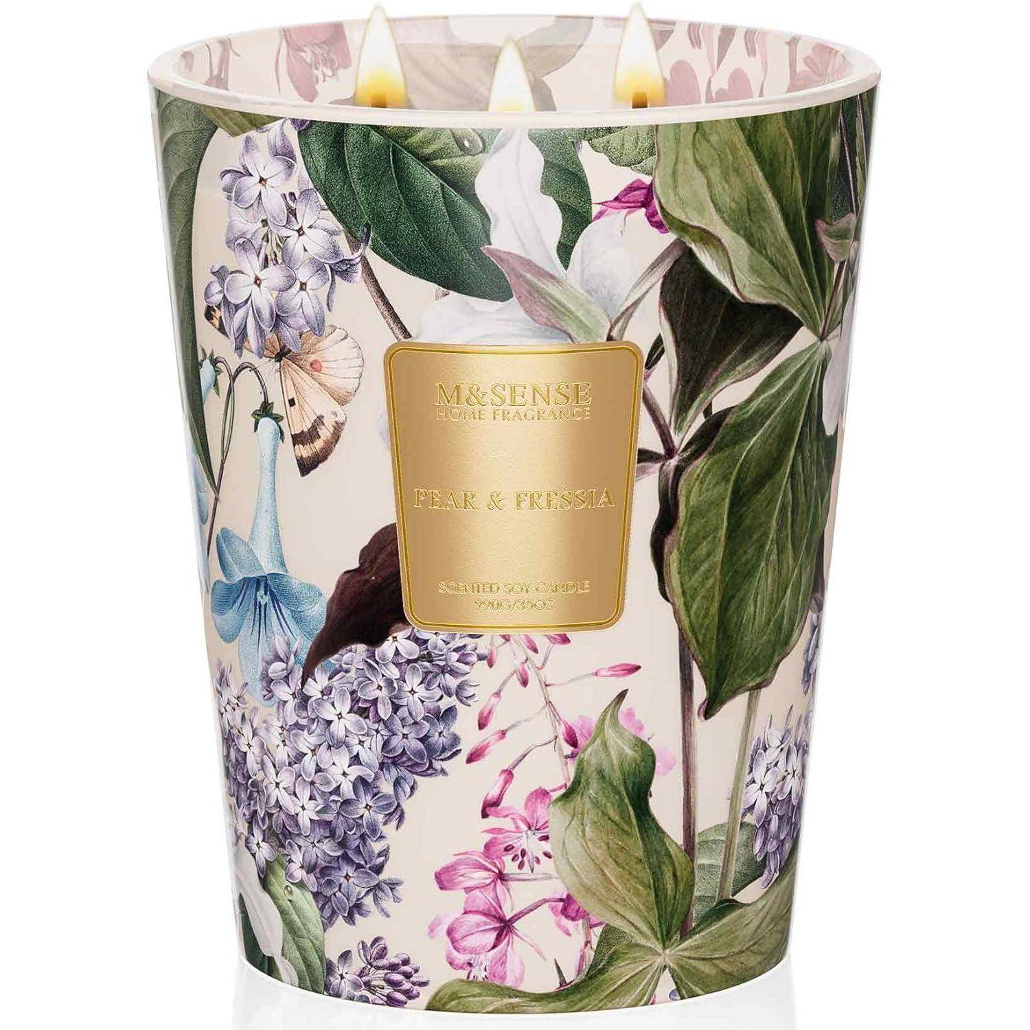 Eine Kerze mit Blumenmuster und drei entzündeten Flammen, beschriftet mit ‚M&SENS Paris Tradition' und ‚Birne & Freesie'.