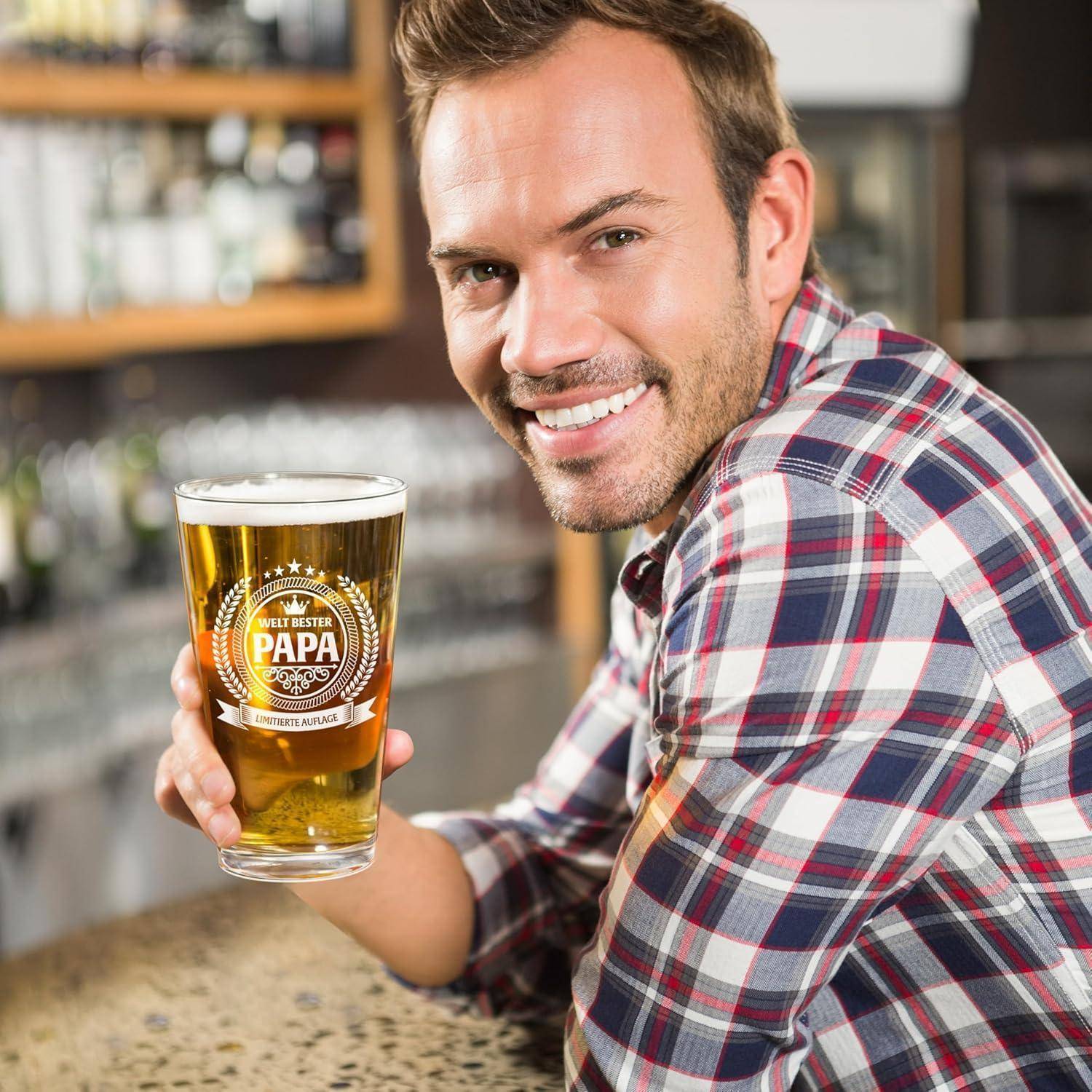 Ein Mann in einem karierten Hemd lächelt, während er ein Bierglas hält und an einer Bar steht.