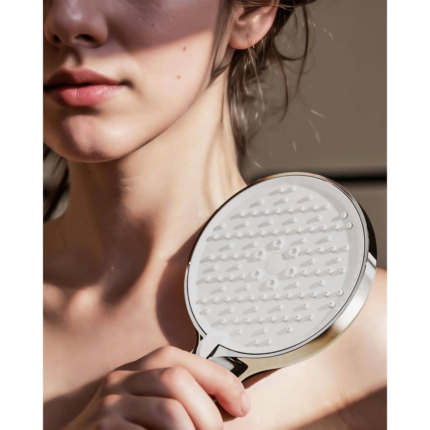 Eine Person, die einen kreisrunden Duschkopf nahe ihrem Gesicht hält, wobei das Sonnenlicht weiche Schatten über ihre Haut wirft und Kontemplation oder Entscheidungsfindung andeutet.