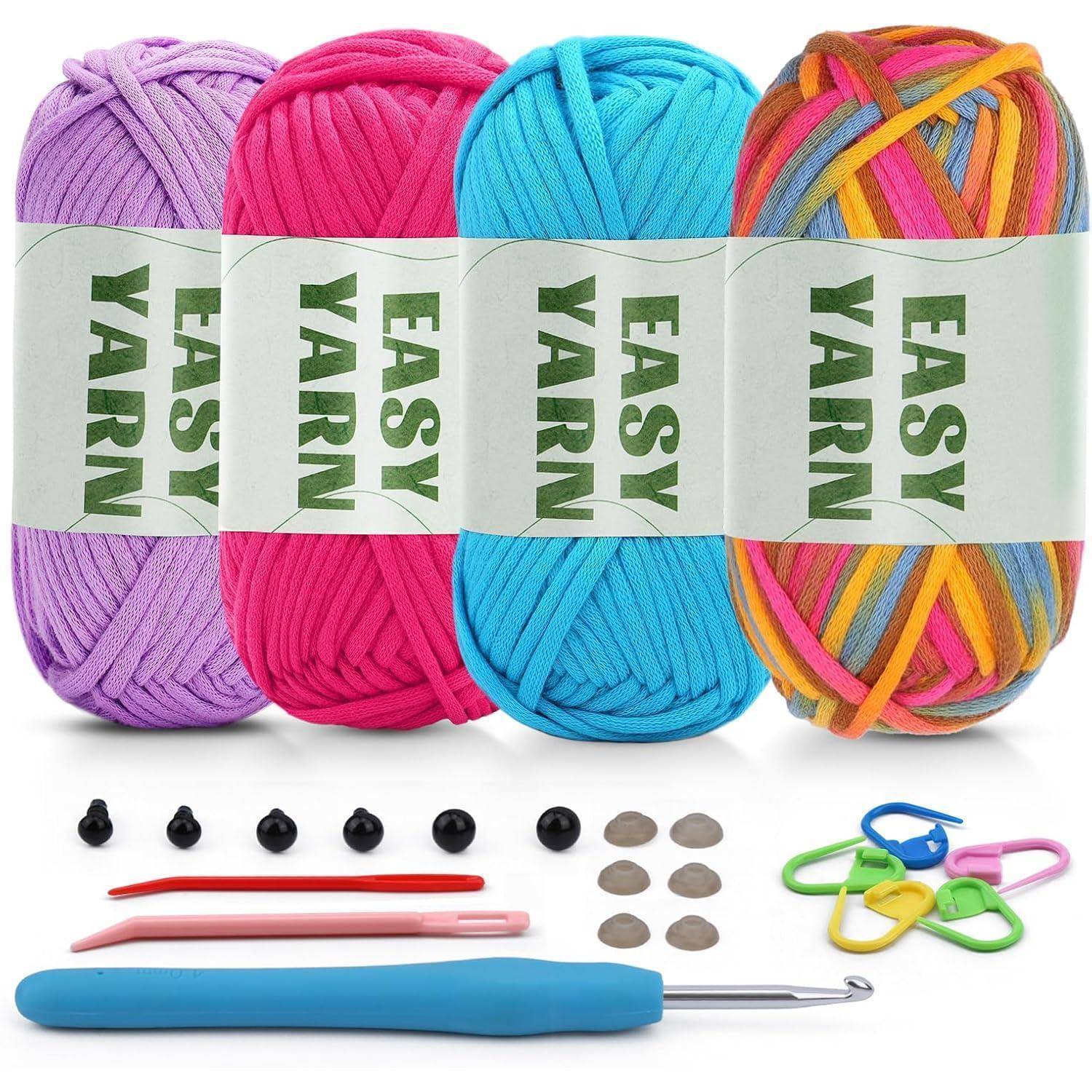 Vier Knäuel Easy Yarn in Lila, Rosa, Blau und Multicolor werden mit Häkelnadeln, Augen und Maschenmarkern in verschiedenen Farben gezeigt.
