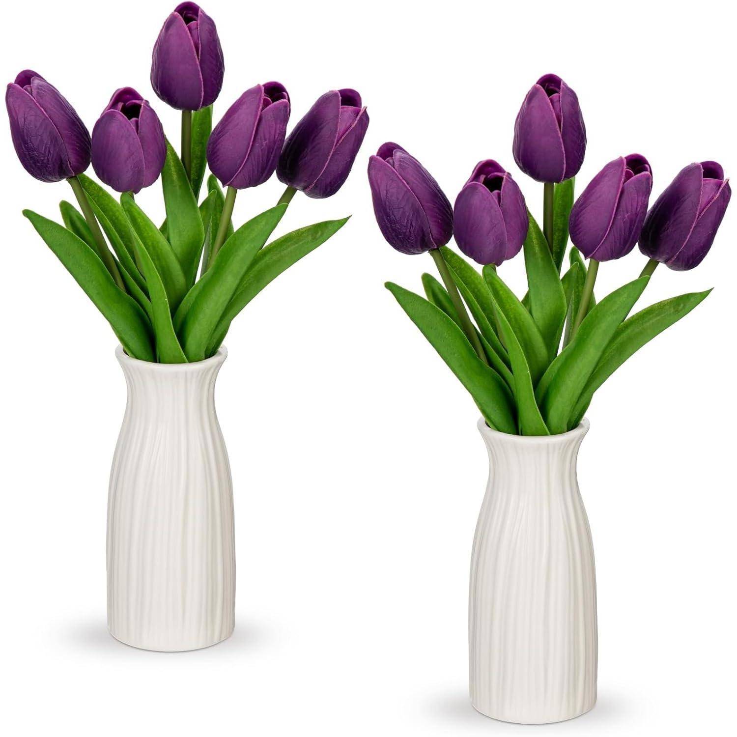 Zwei weiße Vasen halten jeweils einen Blumenstrauß aus violetten Tulpen mit grünen Stängeln und Blättern, künstlerisch angeordnet zu dekorativen Zwecken.