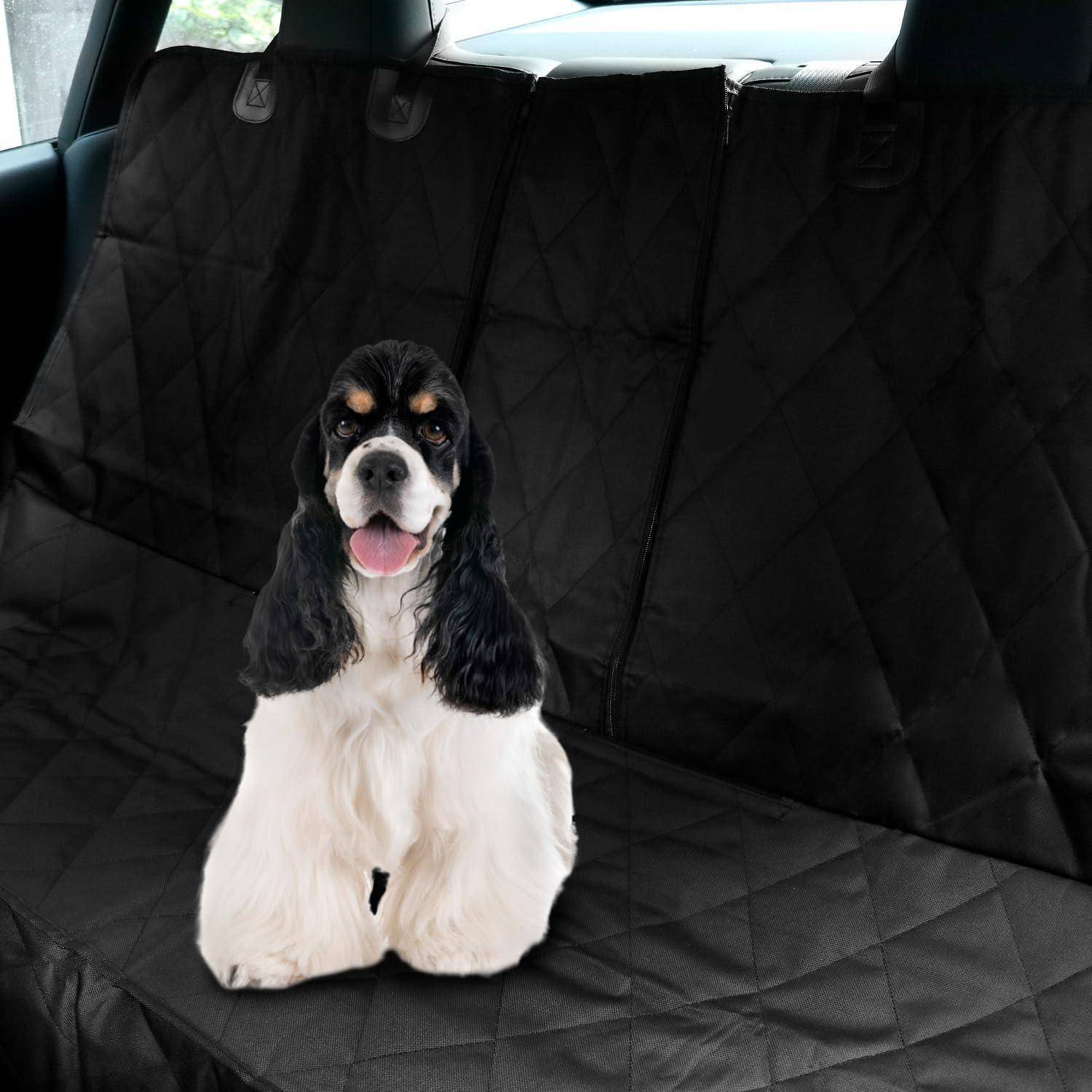 Ein Hund mit einem flauschigen weißen Fell und schwarzen Ohren sitzt auf einer gesteppten schwarzen Sitzauflage im Wageninneren.