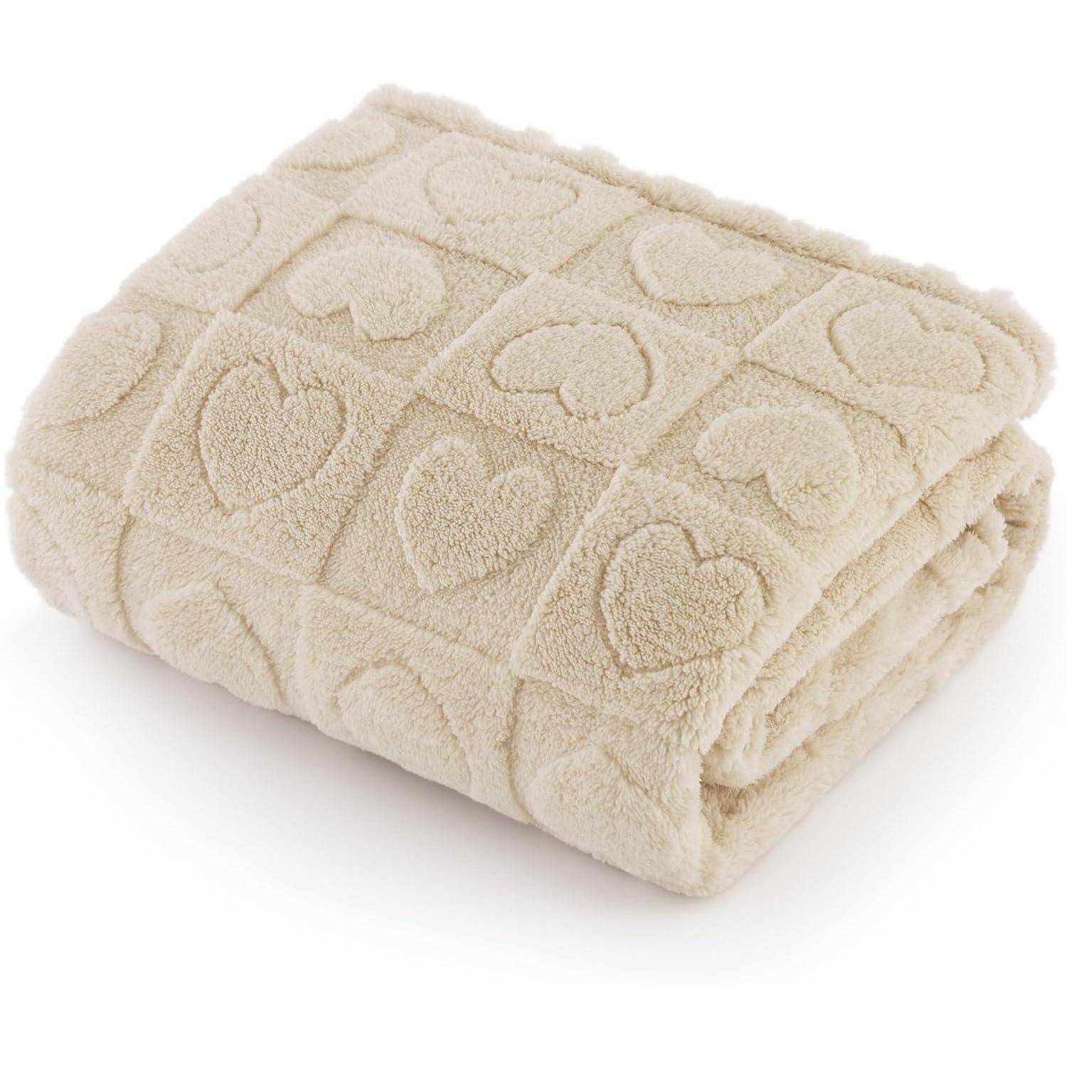 Eine gefaltete beige Decke mit einem strukturierten Muster aus Herzen in einem Gitternetzlayout.