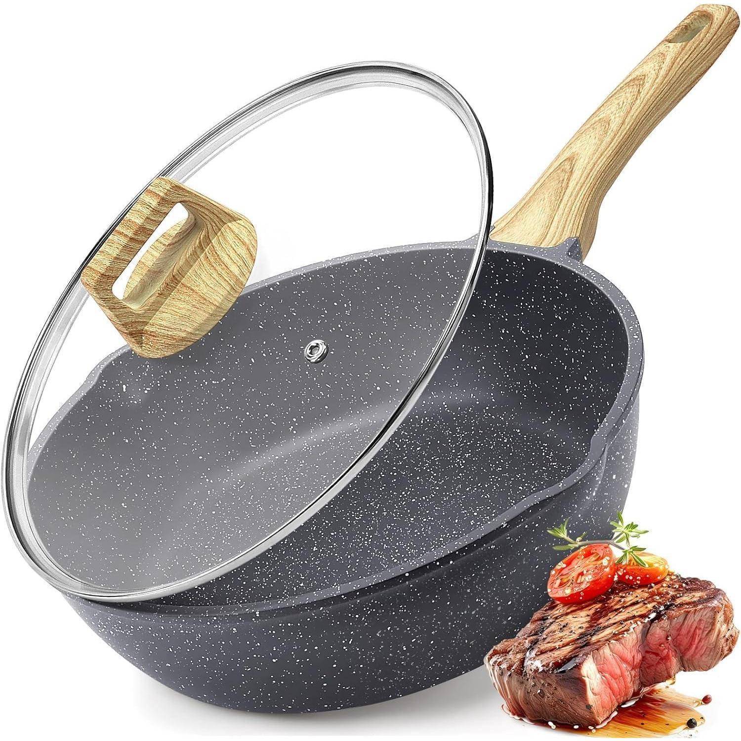 Eine Antihaft-Pfanne mit einem Holzgriff und einem Glasdeckel, neben einem gebratenen Steak, garniert mit Kräutern und Tomatenscheiben.