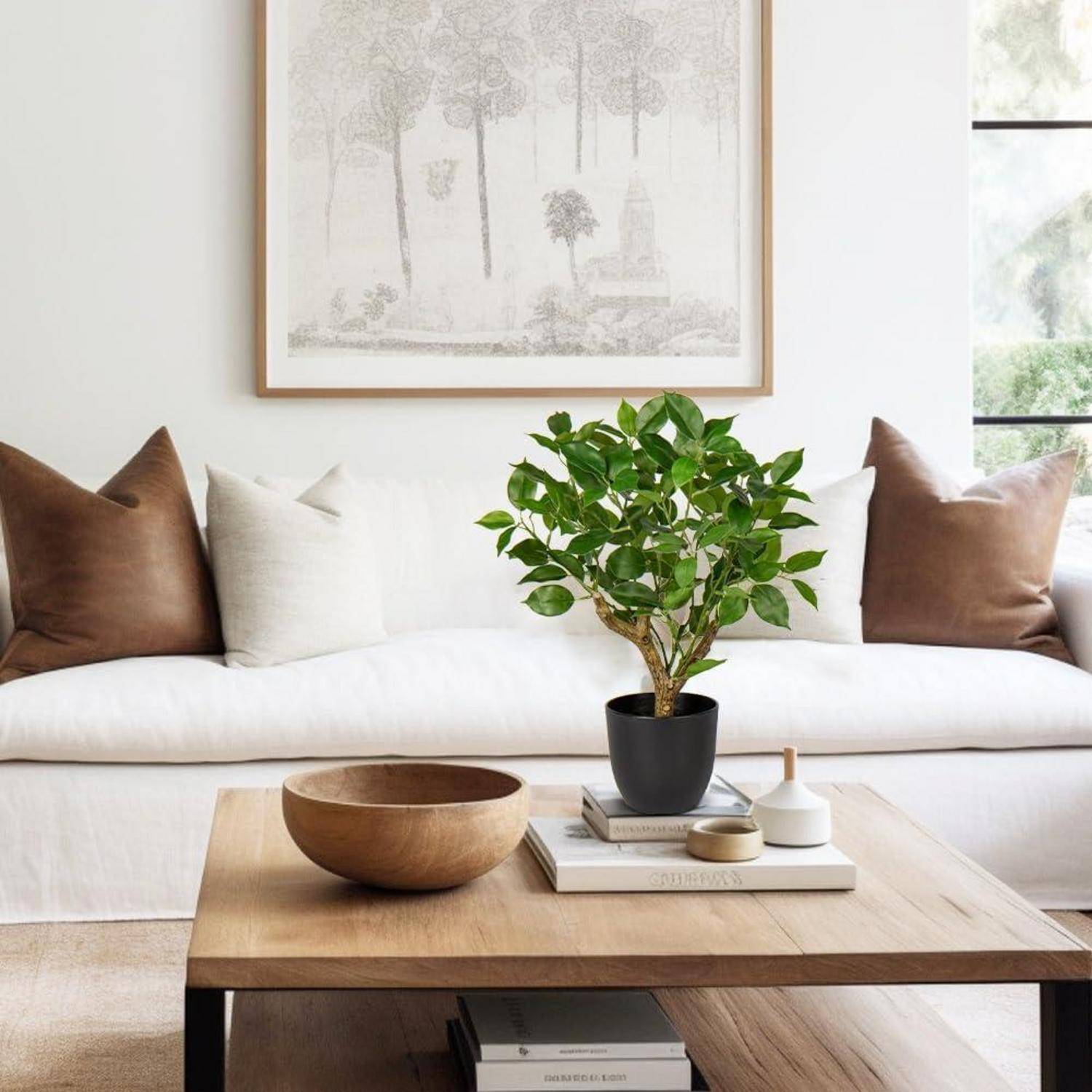 Ein gemütliches Wohnzimmer mit einem weißen Sofa, braunen und weißen Kissen, einem Holzcouchtisch mit einer Topfpflanze, Büchern und kleinen Dekorationselementen.