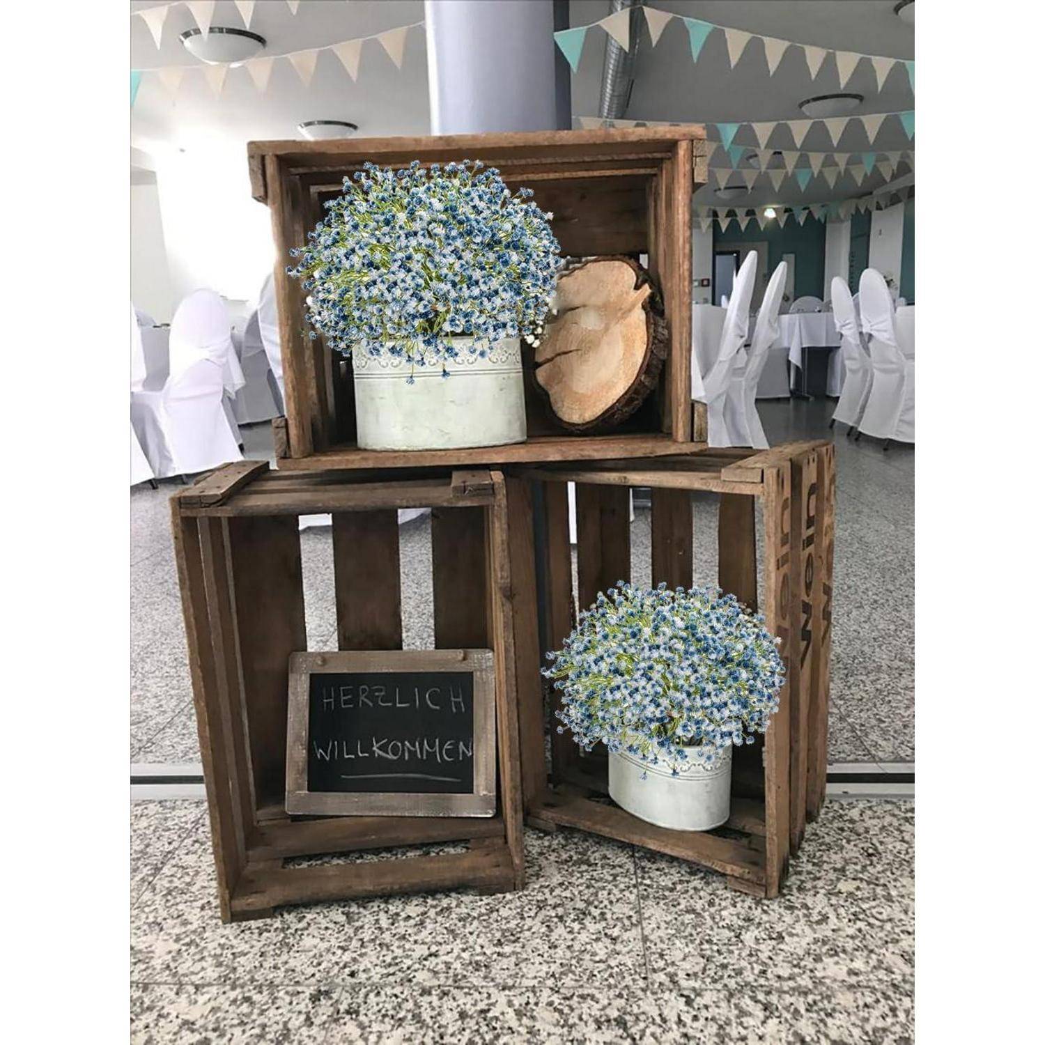 Holzkisten mit Eimern voller blauer Blumen und Baumscheiben. Eine kleine Kreidetafel mit der Aufschrift 