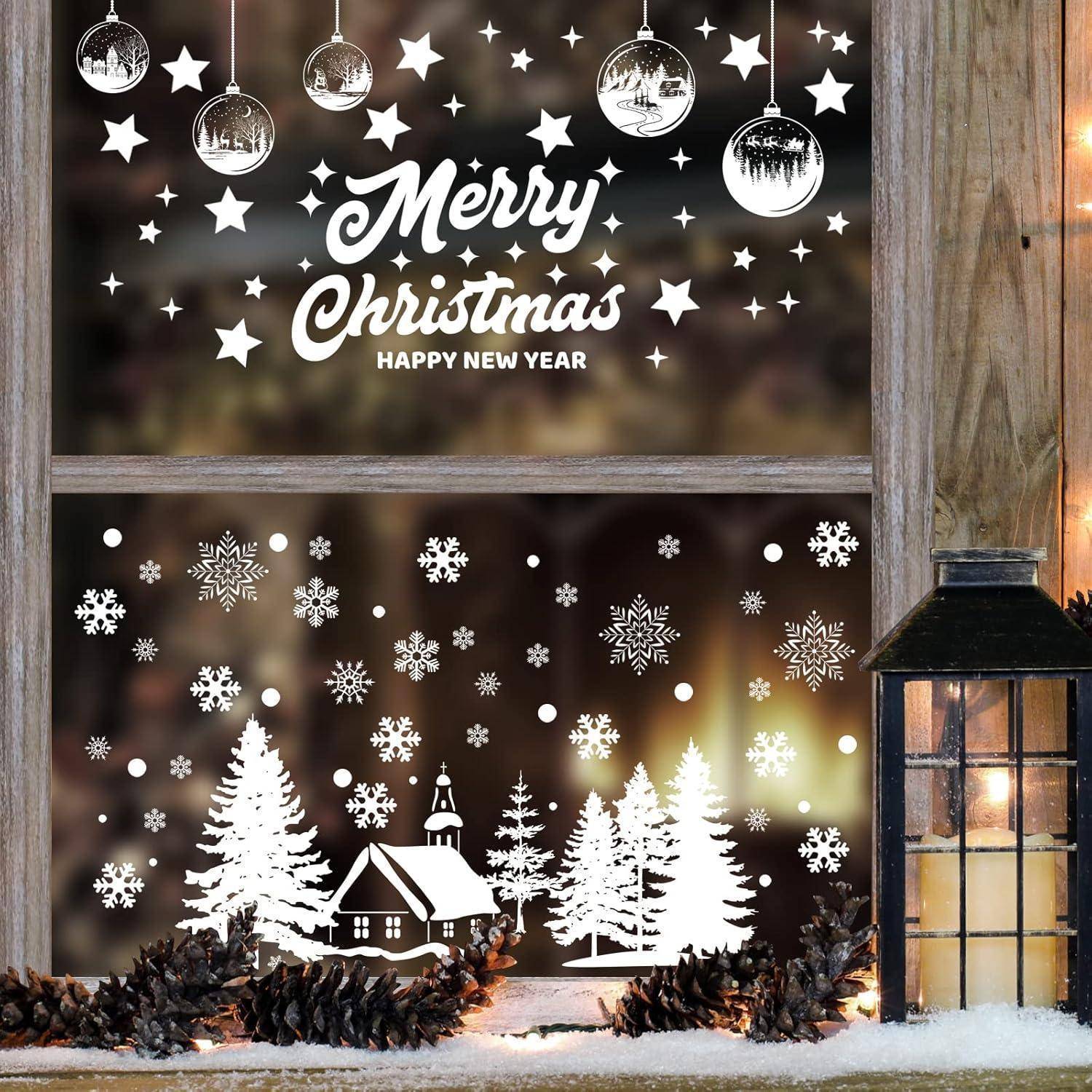 Fenster geschmückt mit festlichen Bildern: hängende Christbaumkugeln, Sterne, Schneeflocken und eine verschneite Dorfszene mit Bäumen. Text lautet: „Frohe Weihnachten Frohes Neues Jahr
