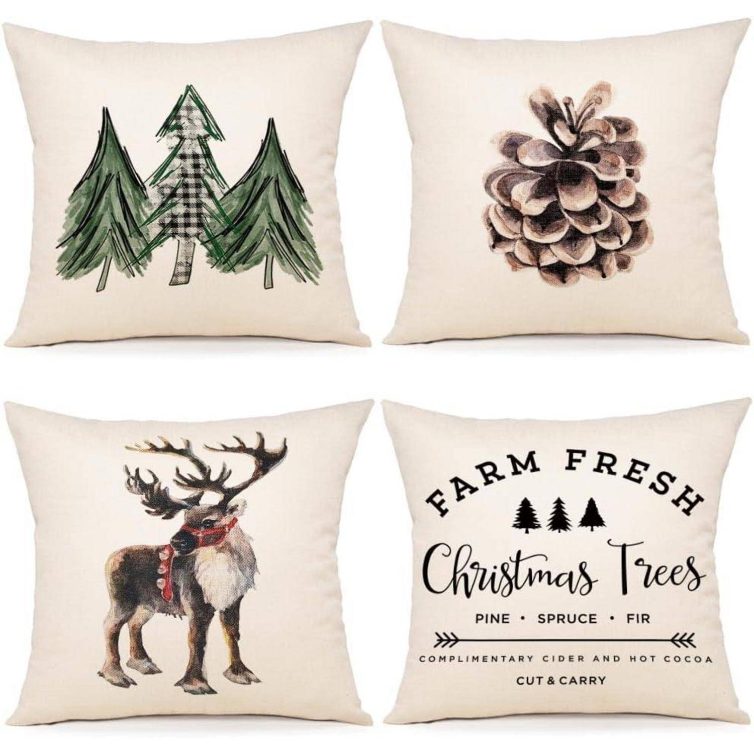 Vier dekorative Weihnachts-Zierkissen. Designs umfassen Bäume, einen Tannenzapfen, ein Rentier und den Text 