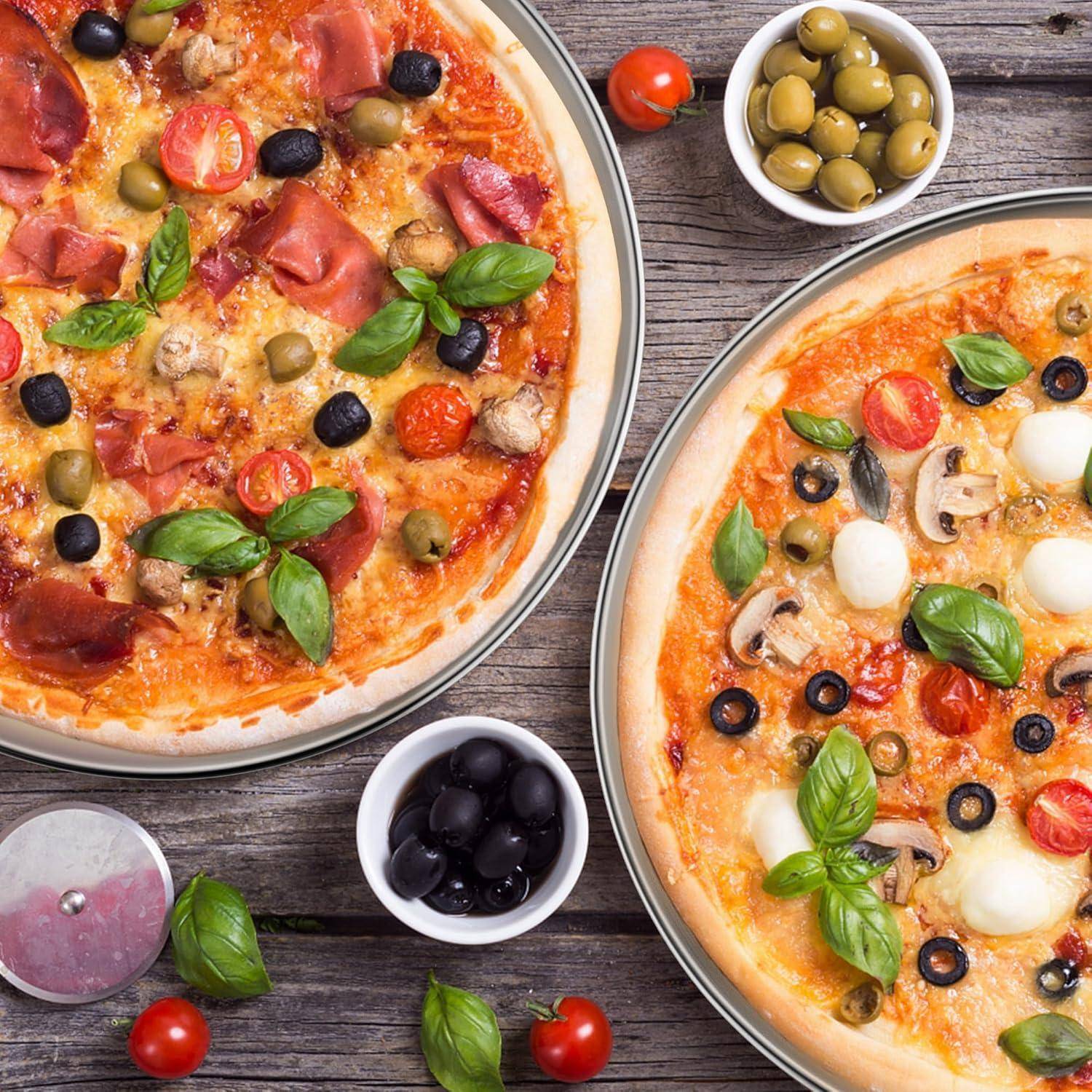 Zwei Pizzen auf einem Holztisch, eine belegt mit Prosciutto, Oliven und Basilikum, die andere mit Pilzen und Oliven. Schalen mit grünen und schwarzen Oliven in der Nähe.