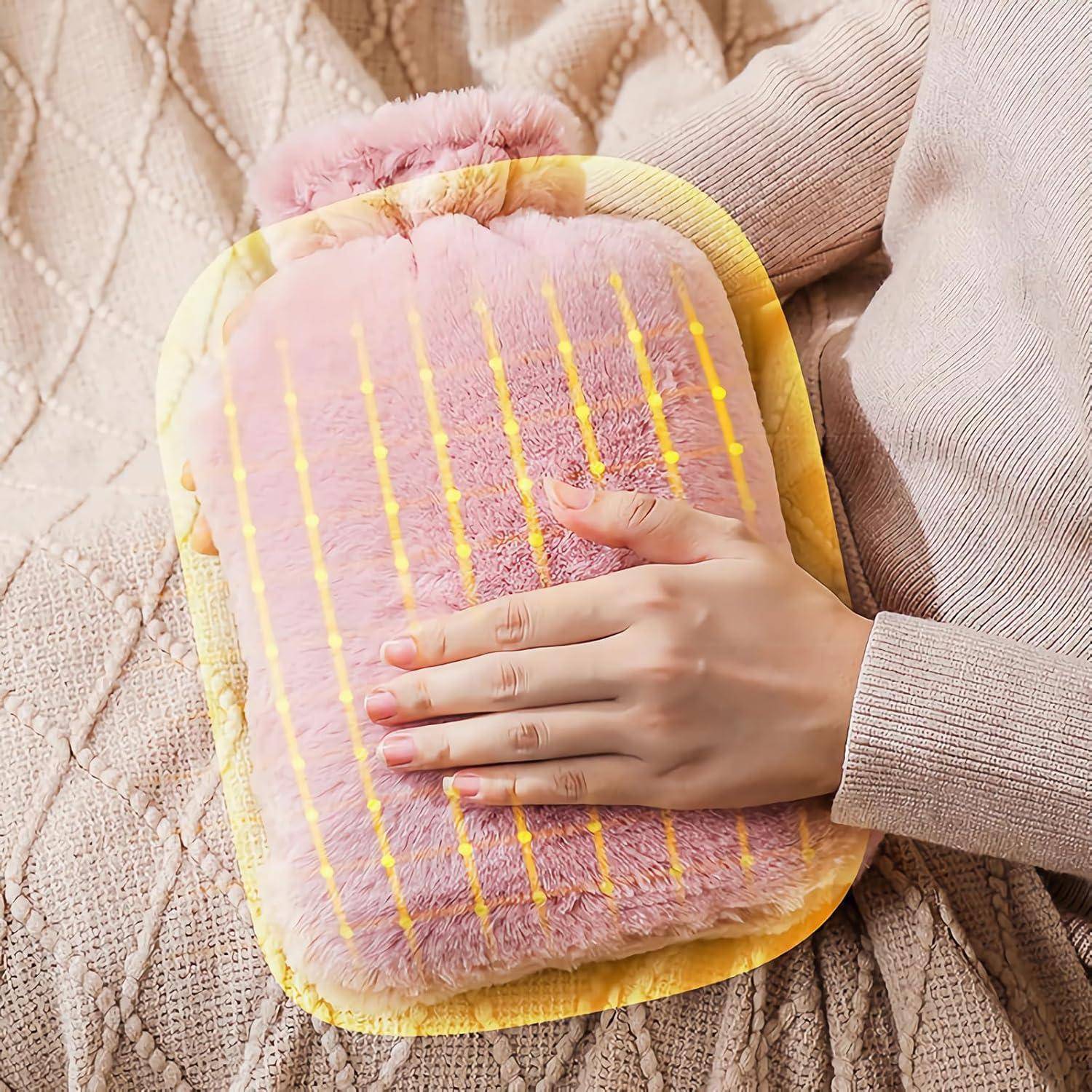 Eine Hand ruht auf einer pinkfarbenen, flauschigen Wärmflasche mit gelben Streifen, die auf einer gestrickten Decke liegt.