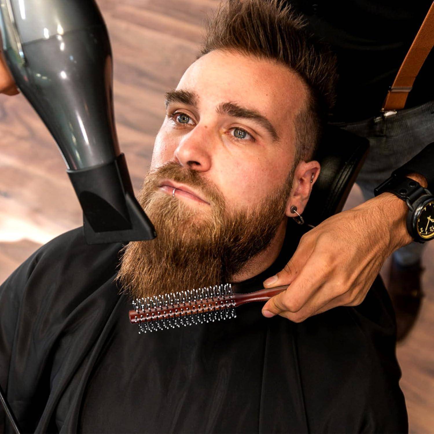 Eine Person mit einem vollen Bart bekommt einen Haarschnitt in einem Friseursalon. Ein Friseur kämmt den Bart, während er einen Föhn verwendet, um ihn zu stylen.
