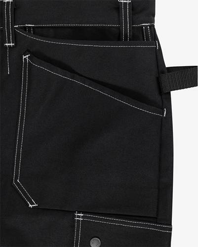 Nahaufnahme eines schwarzen Kleidungsstücks mit Nahtdetails und Riemengestaltung, möglicherweise für zweckmäßige Kleidung oder ein Accessoire wie eine Schürze verwendet.