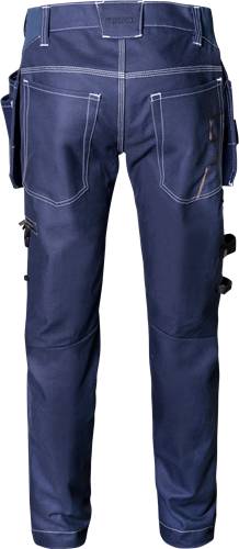 Nahaufnahme von blauen Jeanshosen mit weißen Nähten und Knieflicken, getragen von einer stehenden Person, von der Taille bis zu den Knöcheln zu sehen.