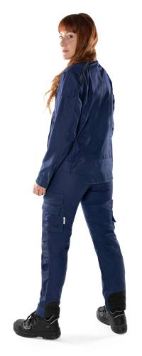 Eine Person trägt eine dunkelblaue Uniform mit mehreren Taschen und steht vor einem einfarbigen Hintergrund, teilweise von der Taille bis zu den Knien abgebildet.