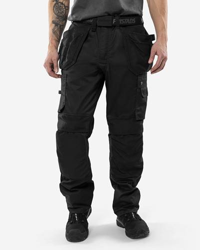 Eine Person trägt schwarze Cargohosen mit mehreren Taschen und steht vor einem einfarbigen Hintergrund. Der Fokus liegt auf dem Hosentypus und Design.