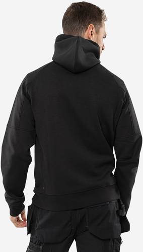 Eine Person mit einem dunklen Hoodie wird von hinten vor einem einfarbigen Hintergrund gesehen.