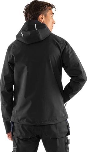 Eine Person in einer schwarzen Kapuzenjacke wird von hinten gezeigt, vor einem einfarbigen schwarzen Hintergrund. Die Jacke hat ein schlichtes, cleanes Design.