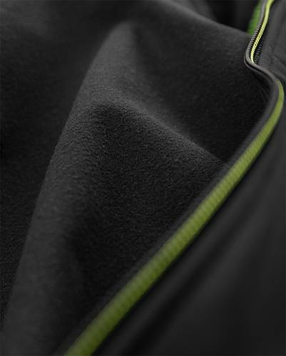 Nahaufnahme eines dunklen Stoffes mit einer sichtbaren Naht, an der ein kontrastierender grüner Reißverschluss angebracht ist.