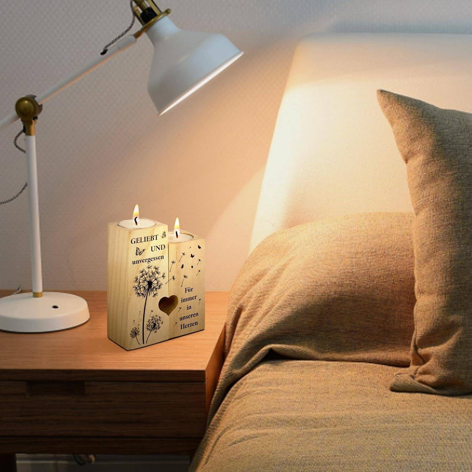 Eine gemütliche Szenerie neben dem Bett mit einer Lampe, Kerzen und einem beigen Bettüberwurf. Die Kerzen haben dekorative Ausschnitte und Text, die eine persönliche Note verleihen.