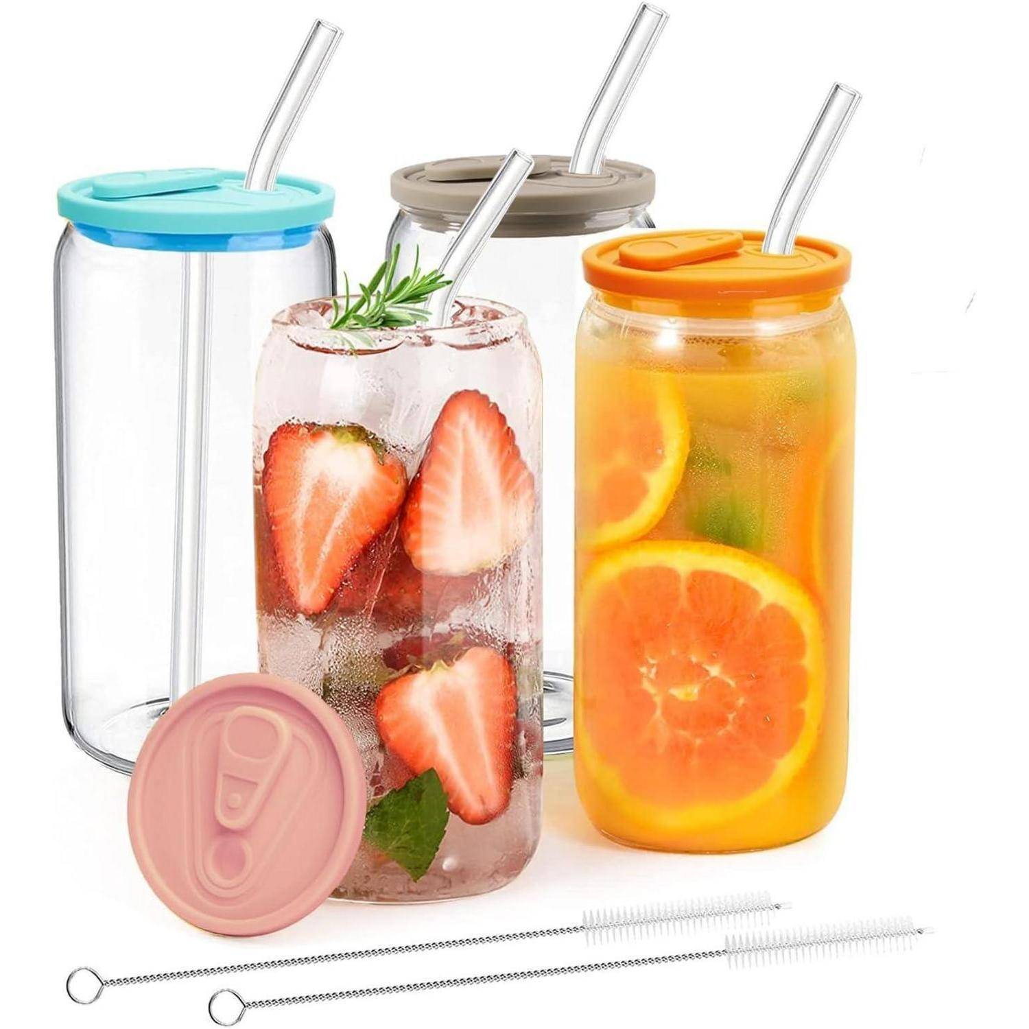 Vier Glasgläser mit bunten Deckeln und Strohhalmen, die jeweils mit unterschiedlichem fruchtinfusiertem Wasser gefüllt sind: Erdbeeren, Orangen und Kräuter.