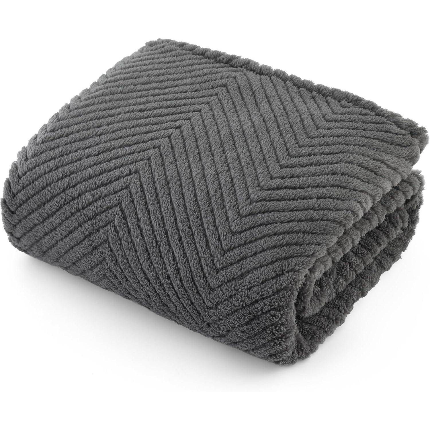 Eine gefaltete, weiche, dunkelgraue Decke mit Zickzackmuster, die ihre Textur und gemütliche Erscheinung betont.