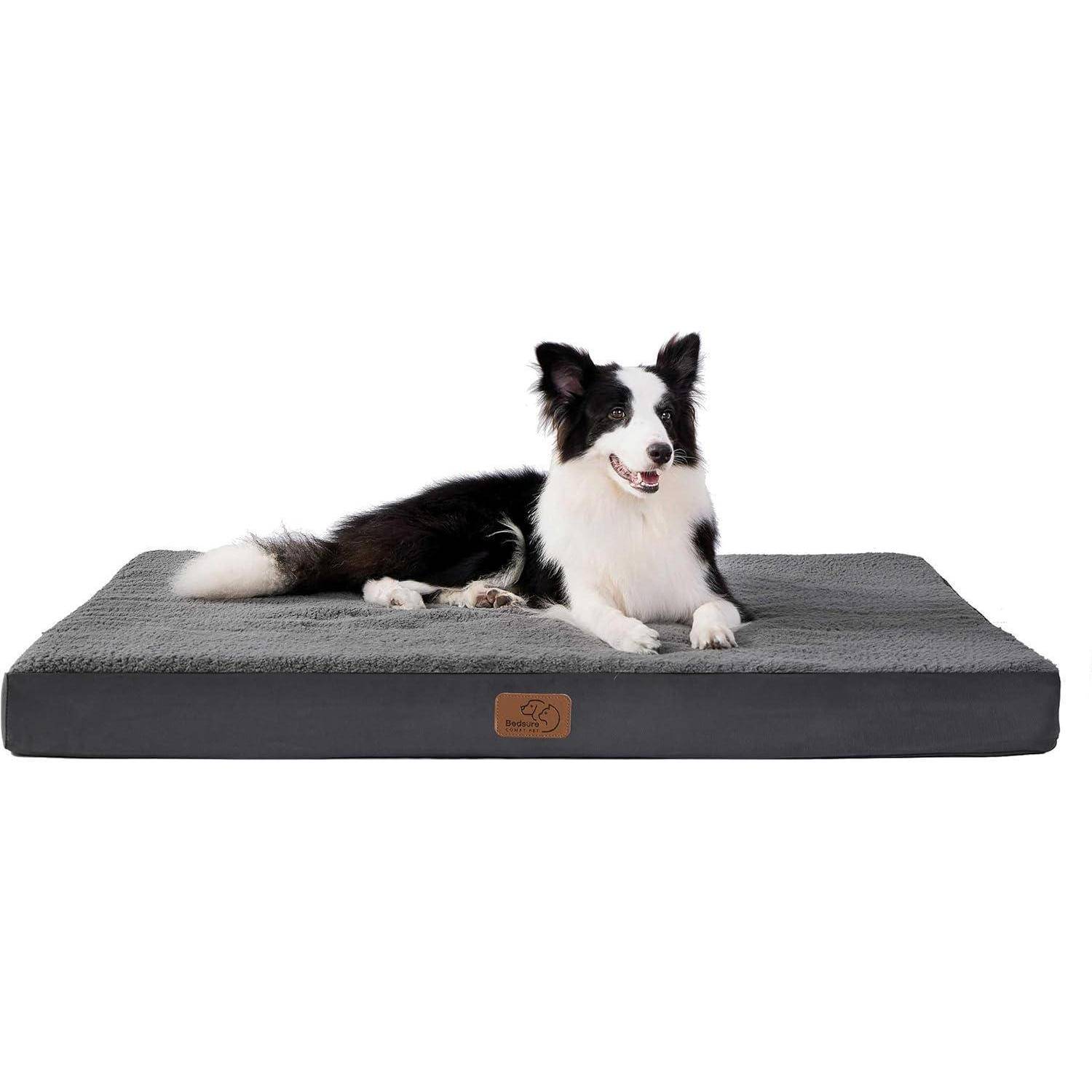 Ein schwarz-weißer Hund liegt auf einem plüschigen, grauen orthopädischen Tierbett mit einem braunen Etikett. Der Hund wirkt entspannt und zufrieden.
