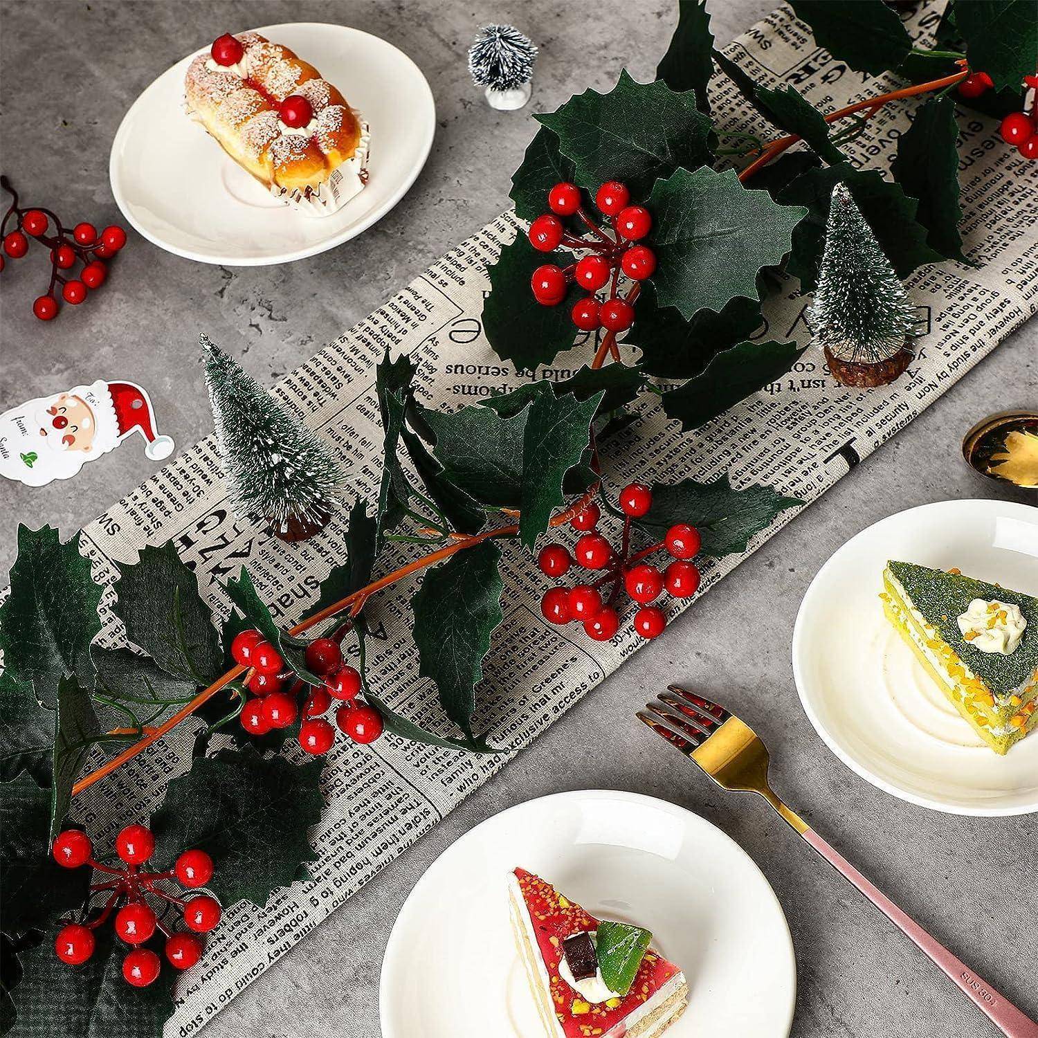 Festlich gedeckter Tisch mit Stechpalmen, Gebäck auf Tellern, einer goldenen Gabel und Feiertagsdekoration auf einer Zeitung, die eine weihnachtlich gestimmte Szenerie schafft.
