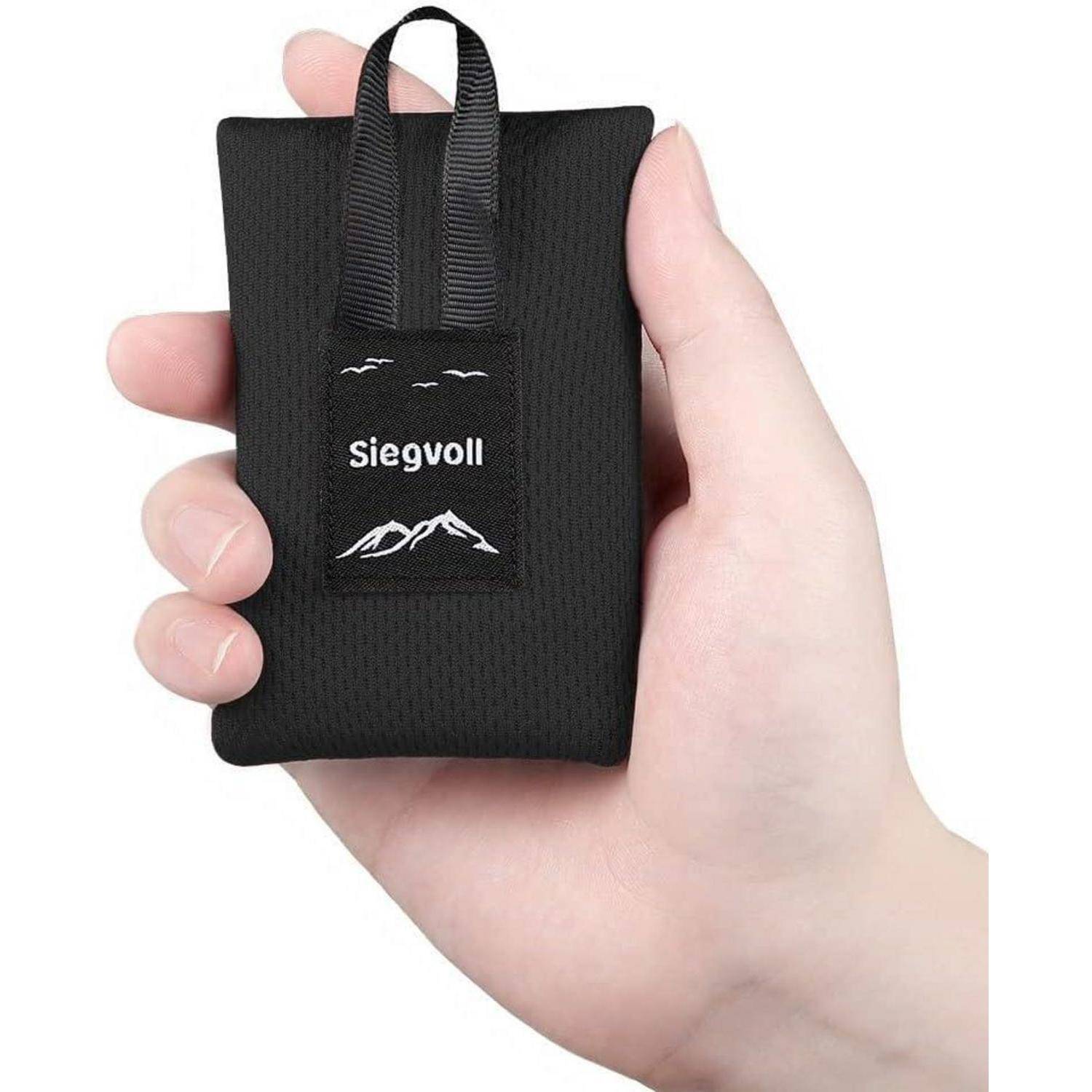 Eine Hand hält eine kompakte, schwarze Tasche mit einem Riemen, der mit der Marke 'Siegvoll' versehen ist und ein Bergmotiv sowie kleine Vögel darüber zeigt.
