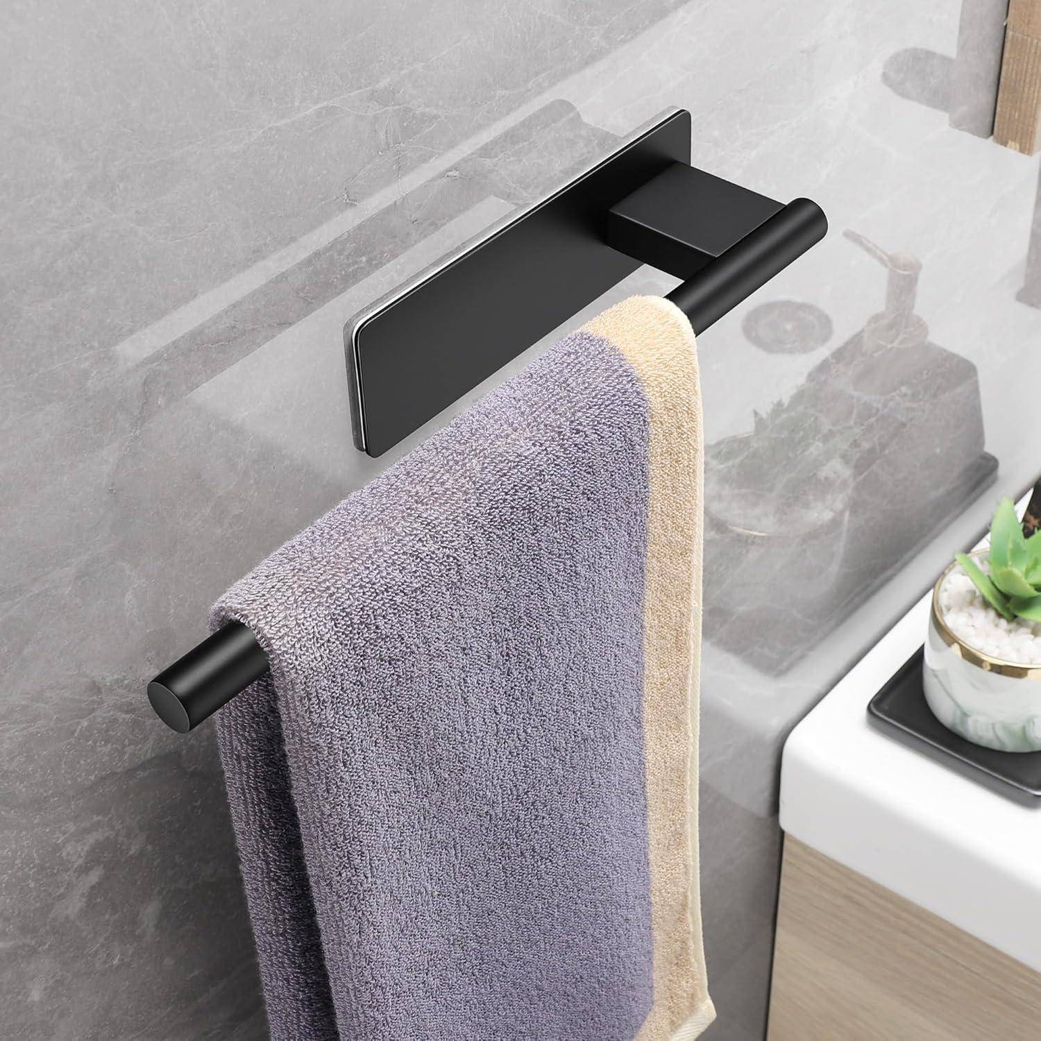 Ein hellviolettes und beiges Handtuch hängt an einer modernen schwarzen Handtuchstange neben einem weißen Waschbecken mit einer Topfsukkulente.