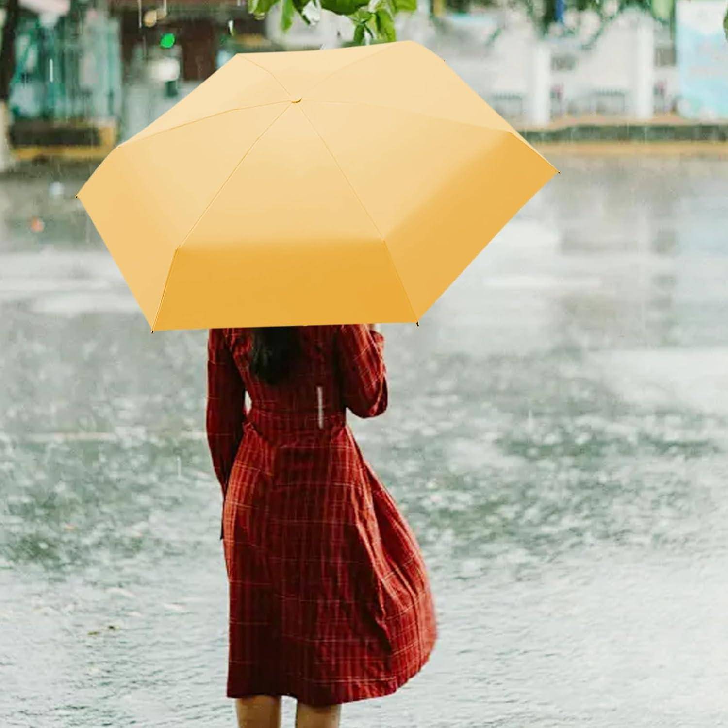 Eine Person in einem roten Karokleid hält einen leuchtend gelben Regenschirm und geht an einem regnerischen Tag weg, während Wassertropfen um sie herum spritzen.
